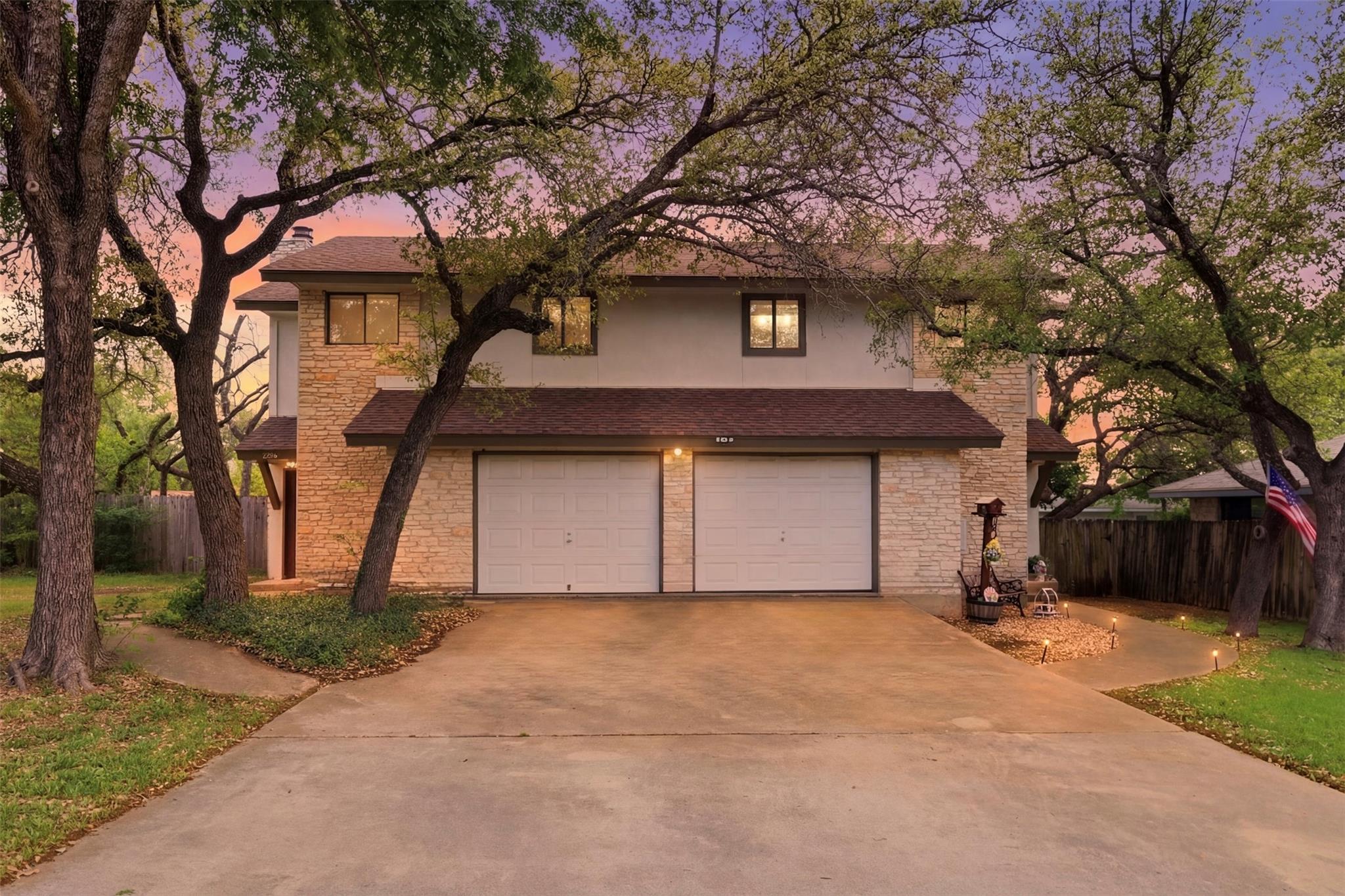 Mature trees frame a classic stone and stucco ext