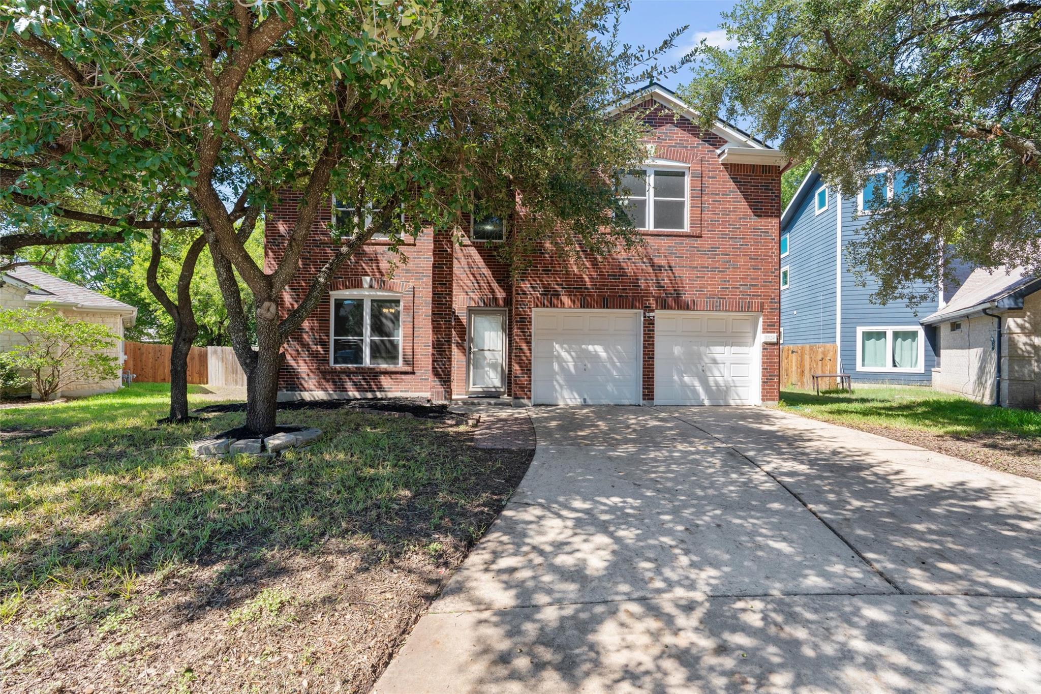 Mature trees shade a classic brick facade featuri