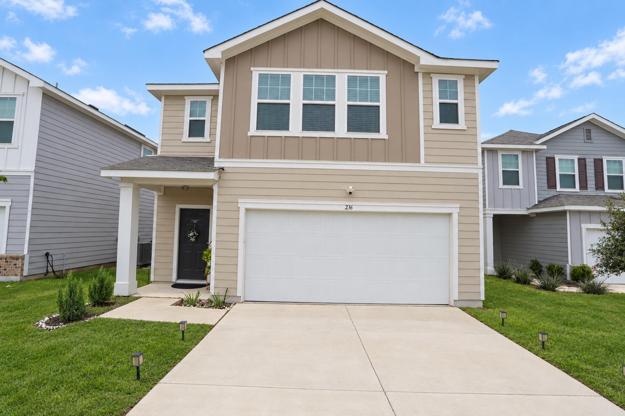A concrete driveway leads past neat lawns to the 