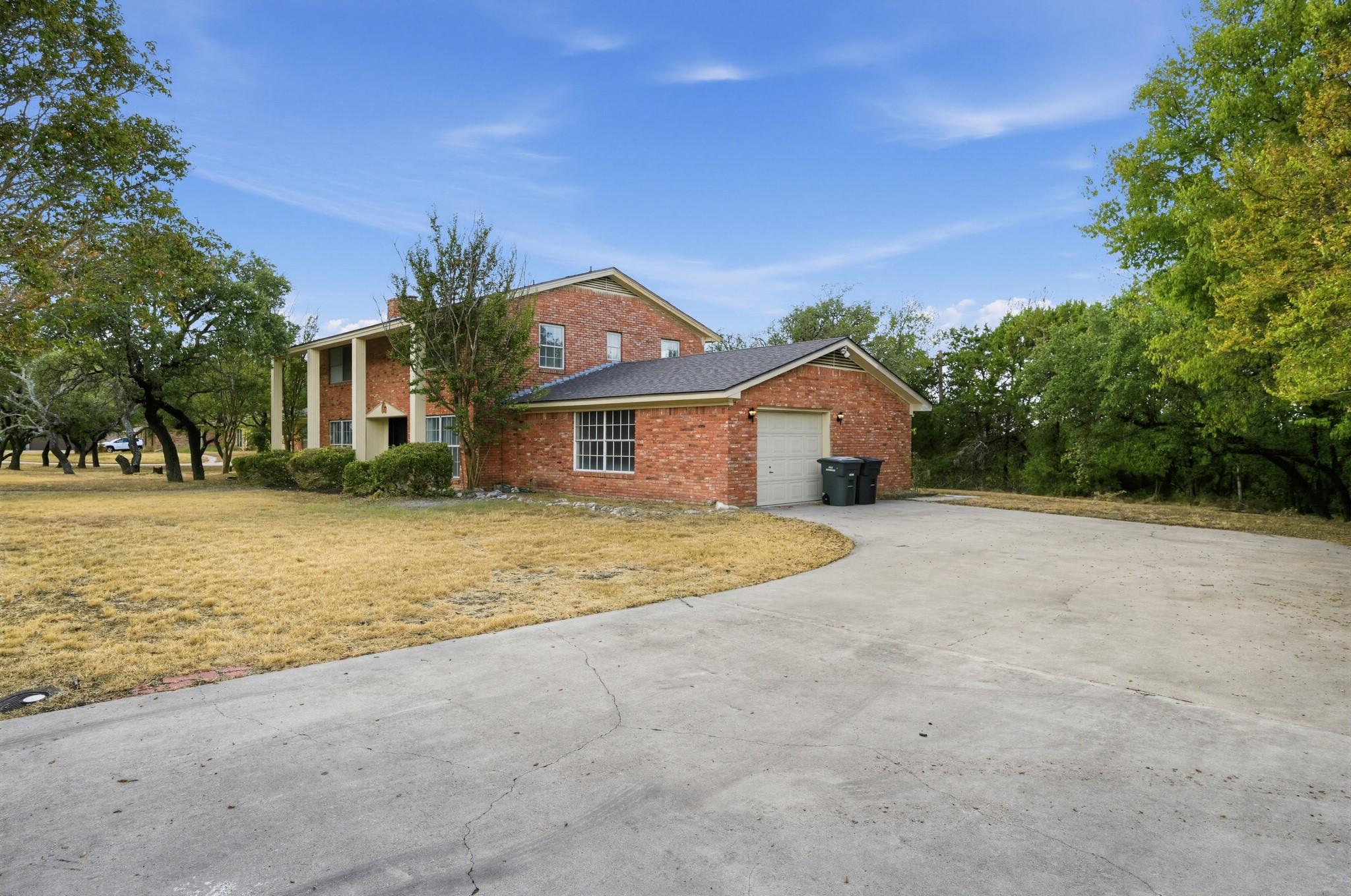Mature trees frame a classic brick exterior compl