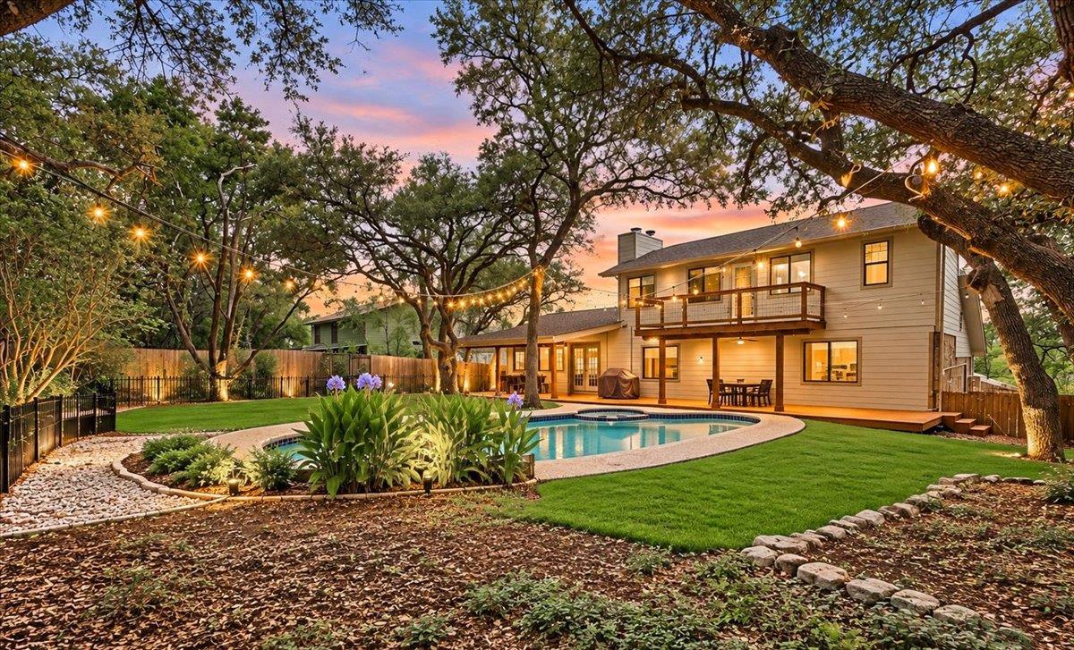 Mature trees frame a private backyard oasis featu