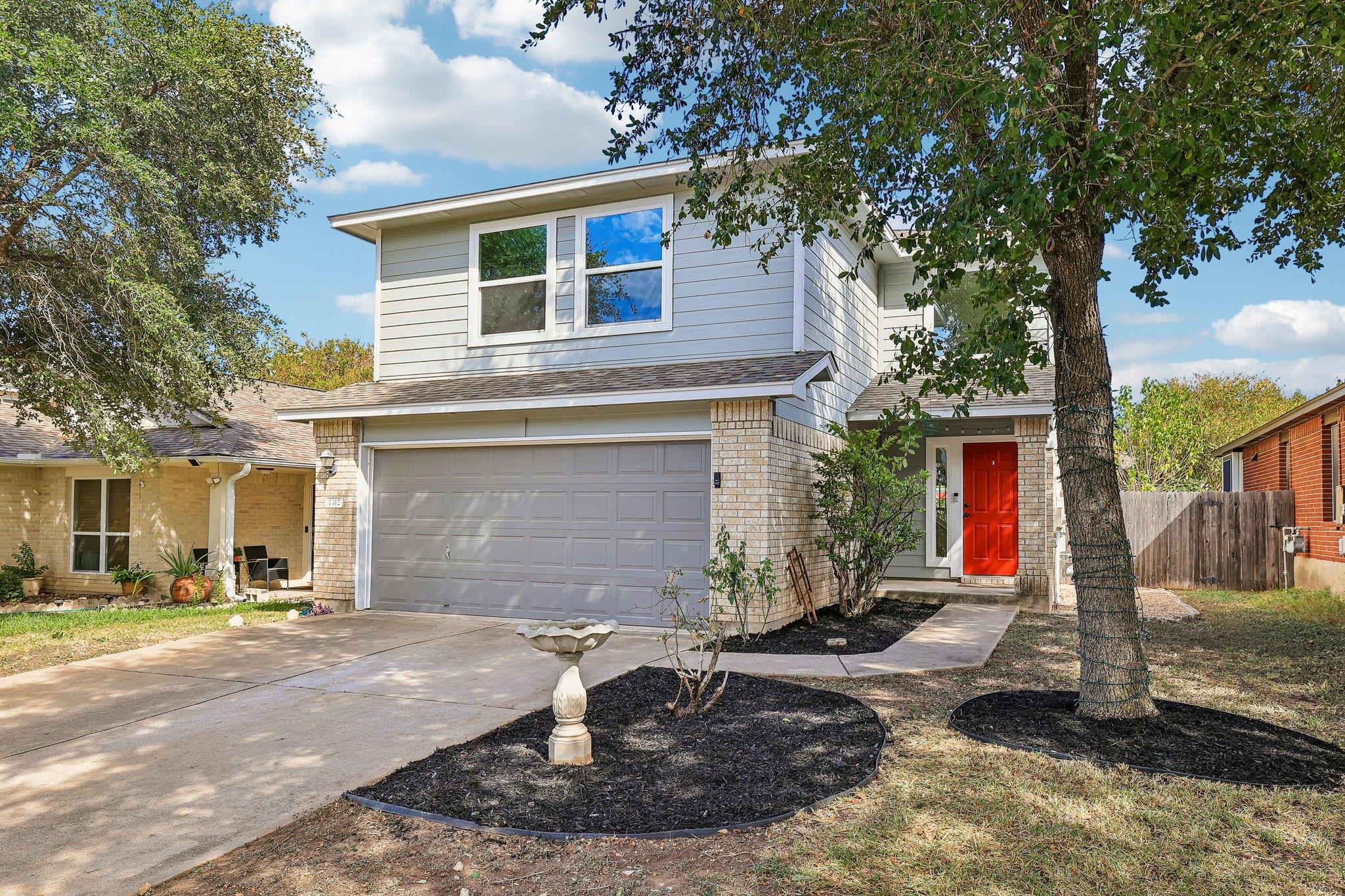 Mature trees shade a tidy front yard leading to a