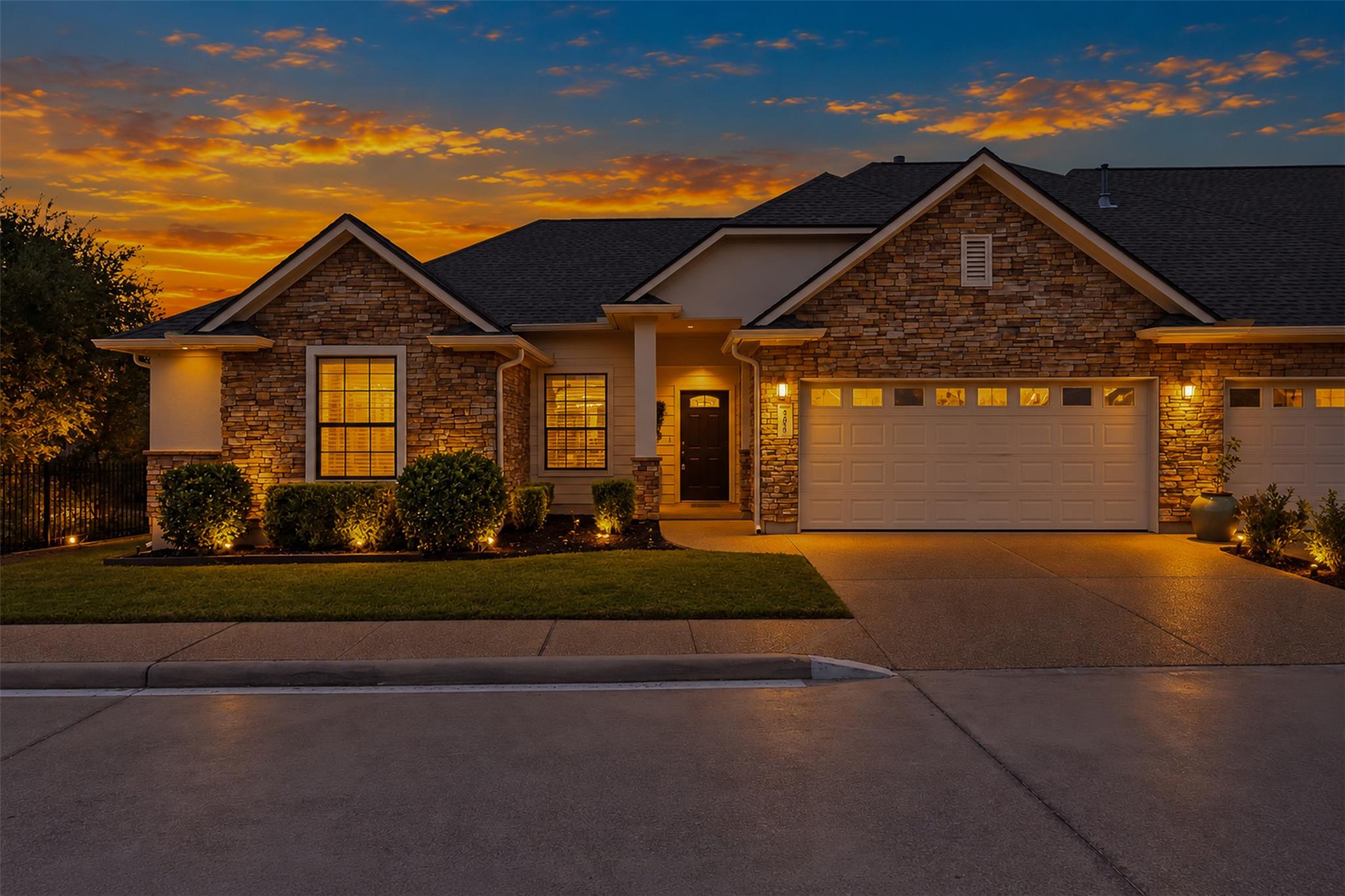 Textured stone siding and a wide driveway frame t