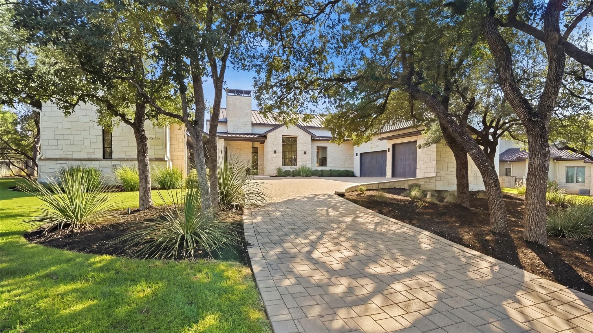 Mature oak trees frame a beautifully paved drivew