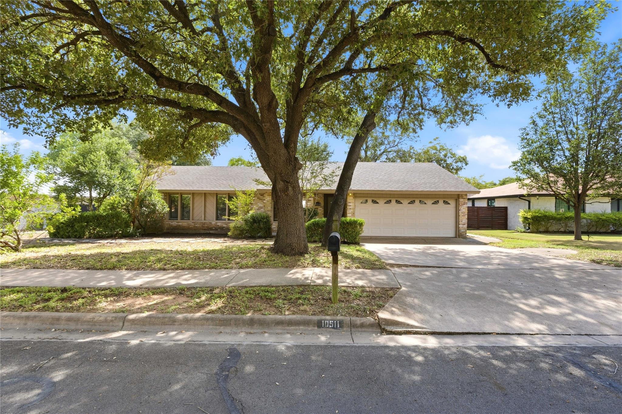 Mature shade trees frame the classic facade and w