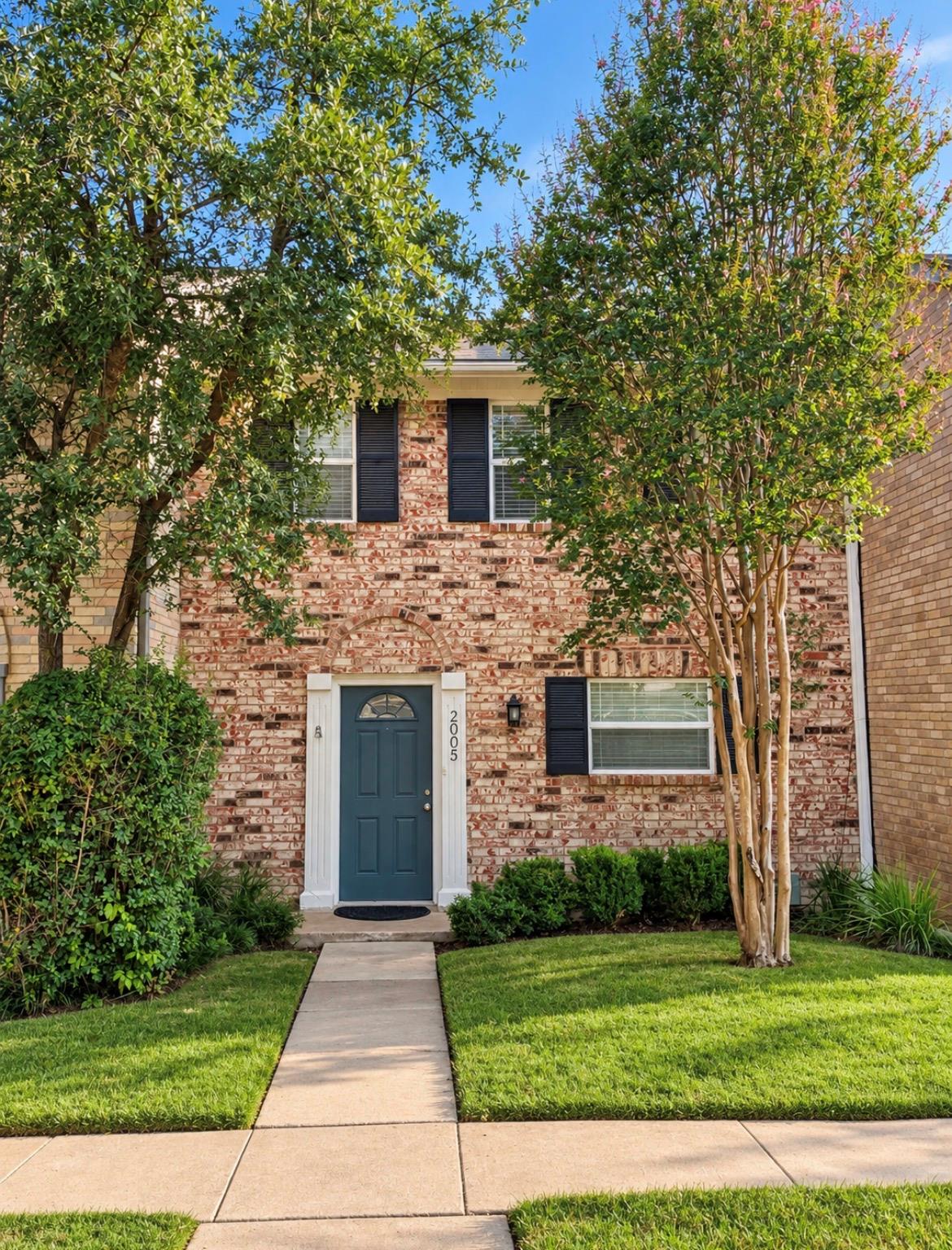 A classic brick exterior framed by mature trees f