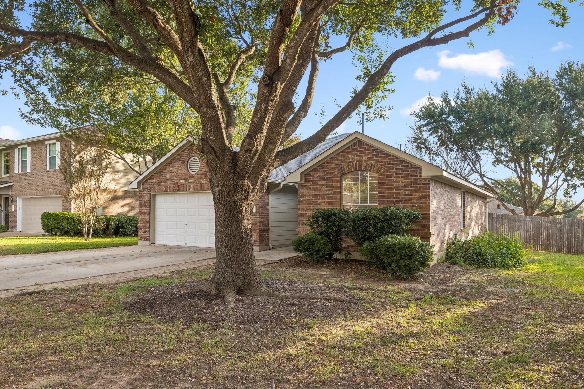 Mature trees shade a classic brick exterior compl