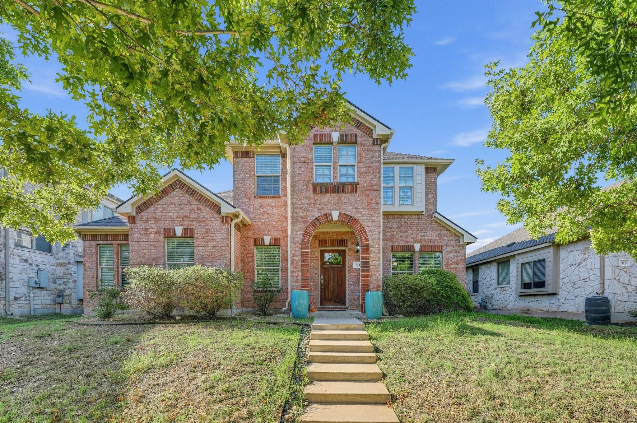 A classic brick exterior stands framed by mature 