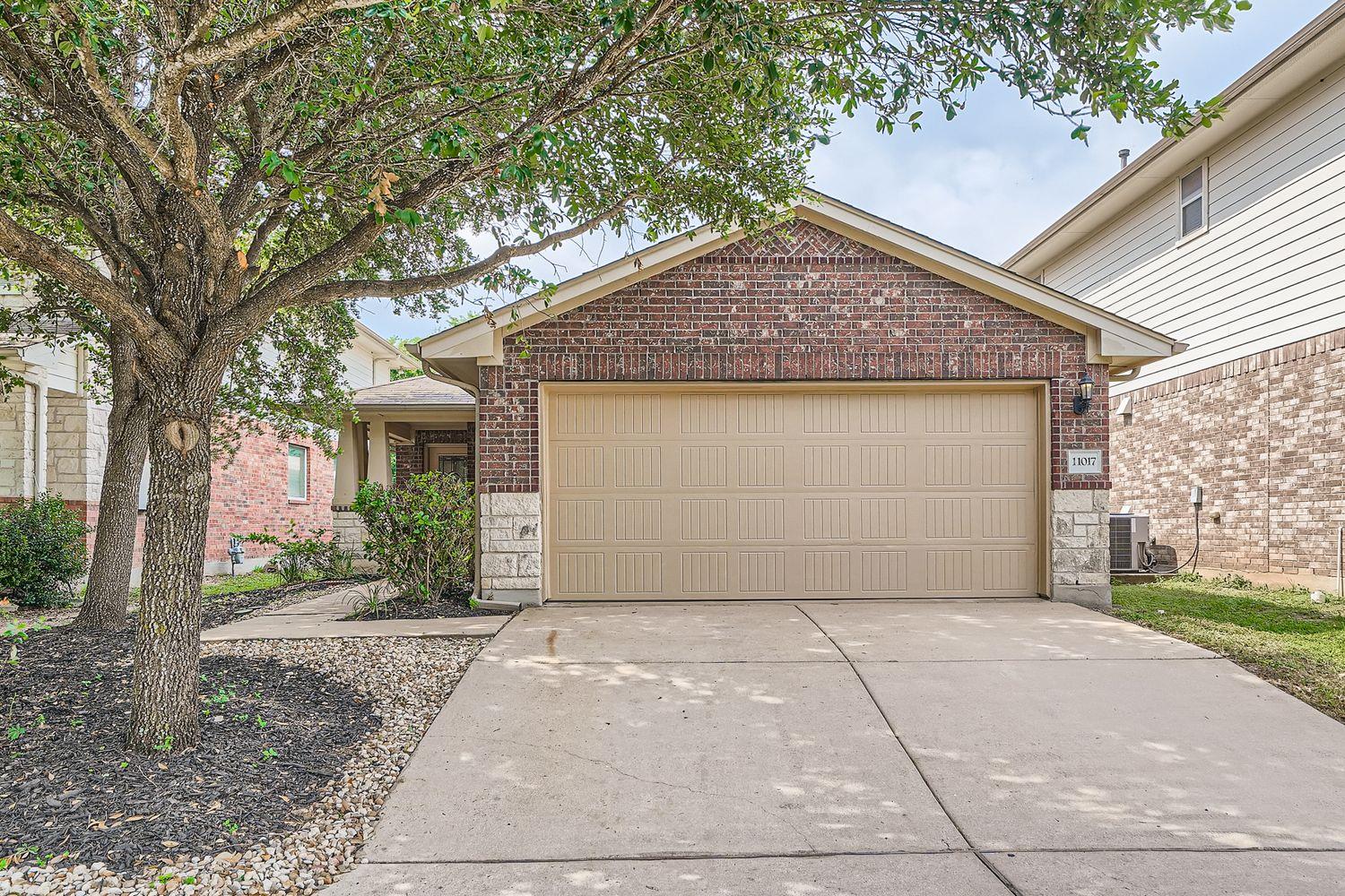 A spacious driveway leads directly to a brick-acc