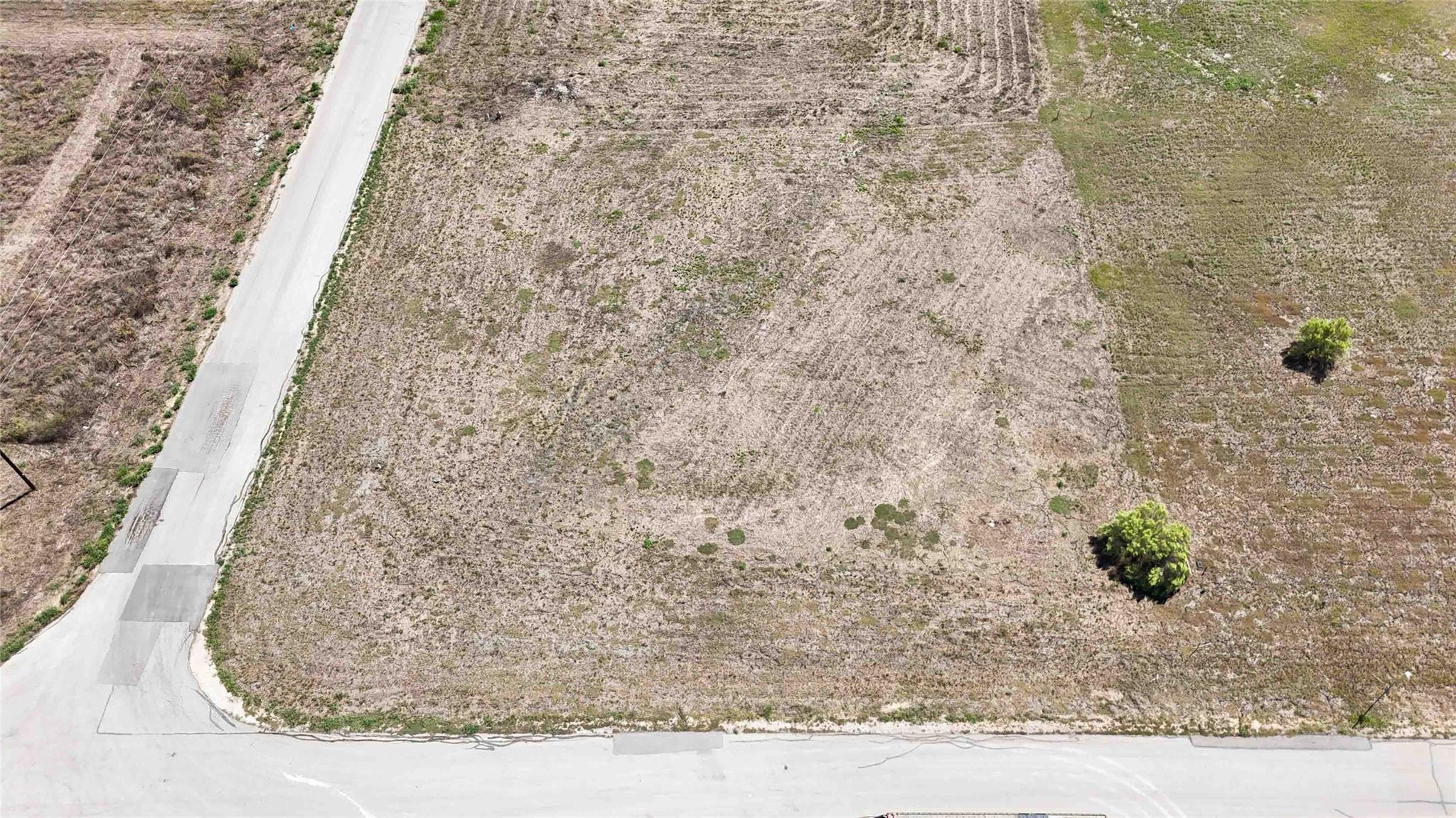A spacious vacant lot bordered by paved roads awa
