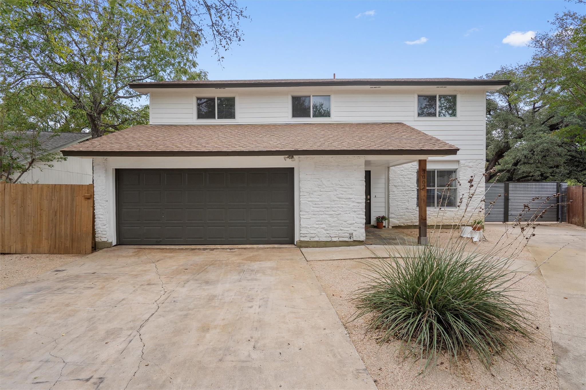 Textured masonry accents and a paved driveway fra