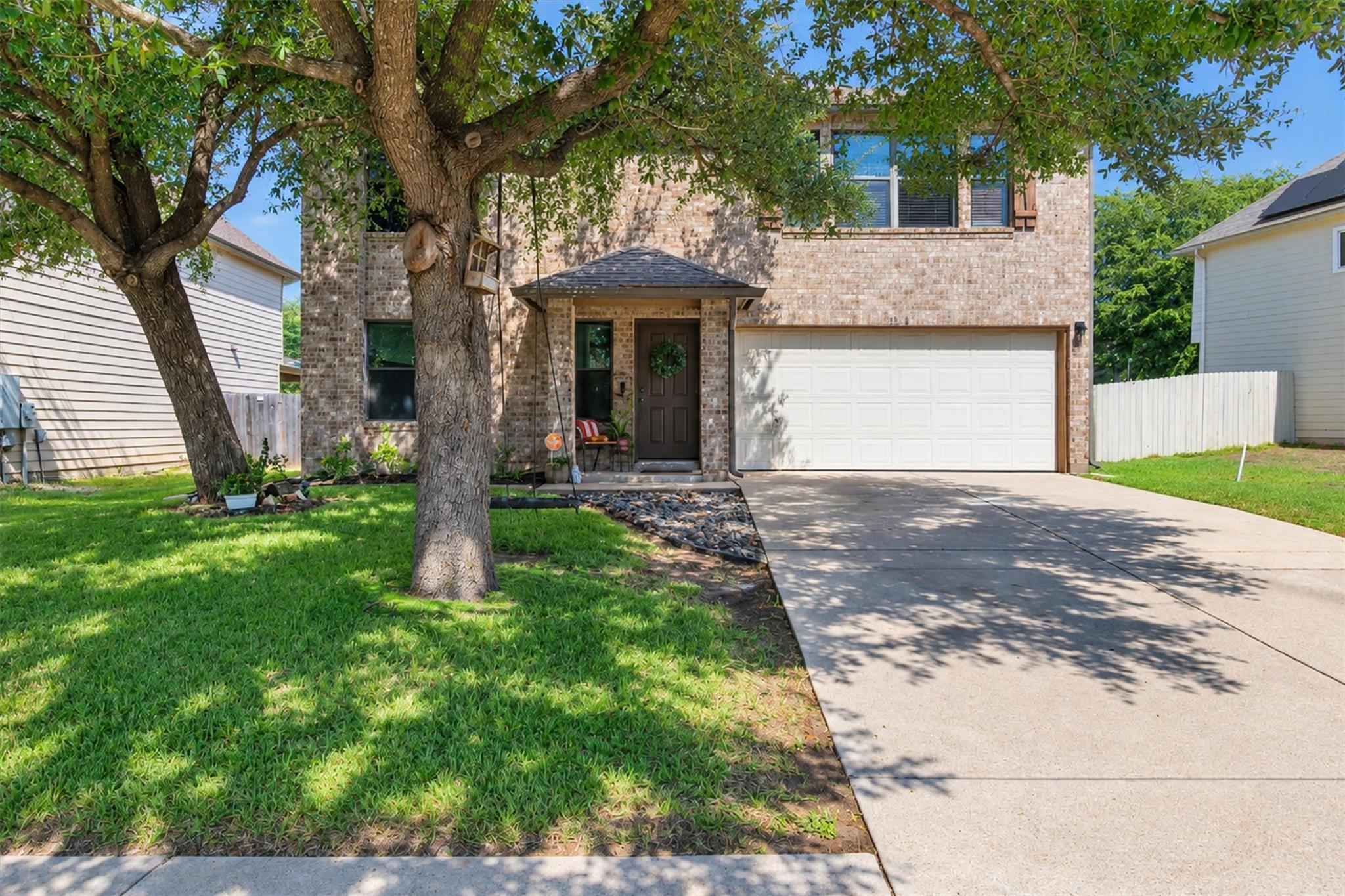 Mature shade trees frame a classic brick facade w
