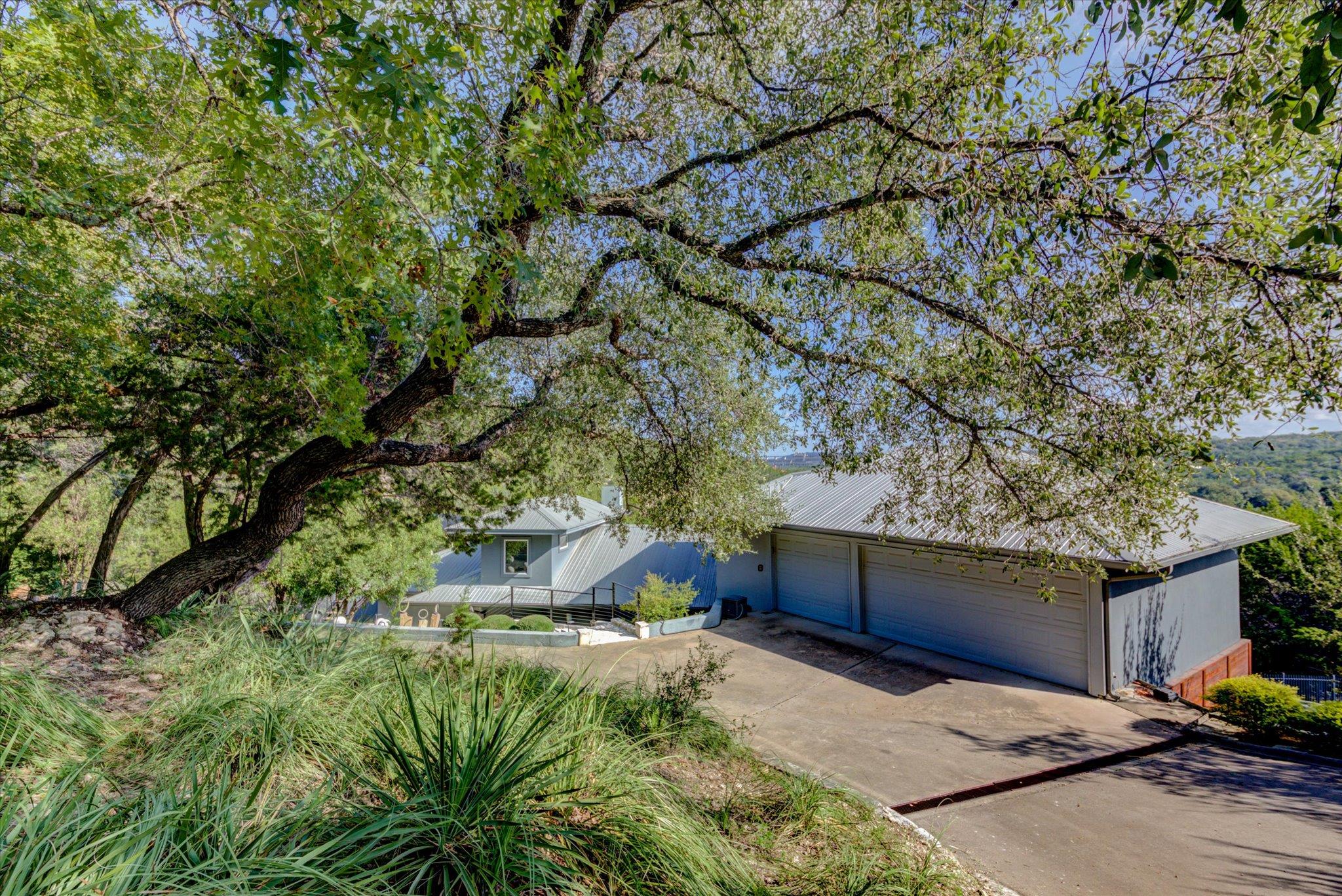 Mature trees shade a spacious driveway leading to