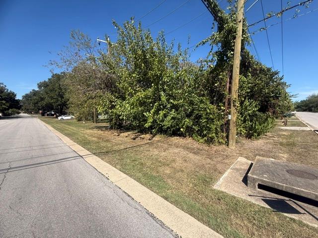 Mature trees and a grassy roadside border this pr