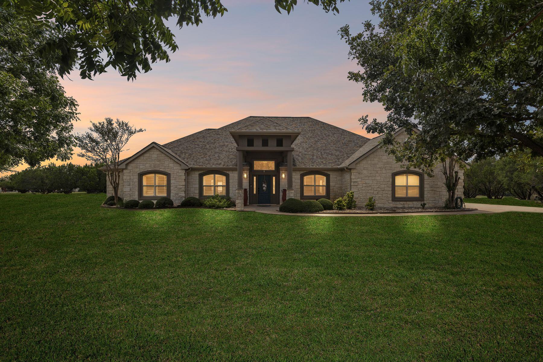An elegant stone facade is nestled among mature t