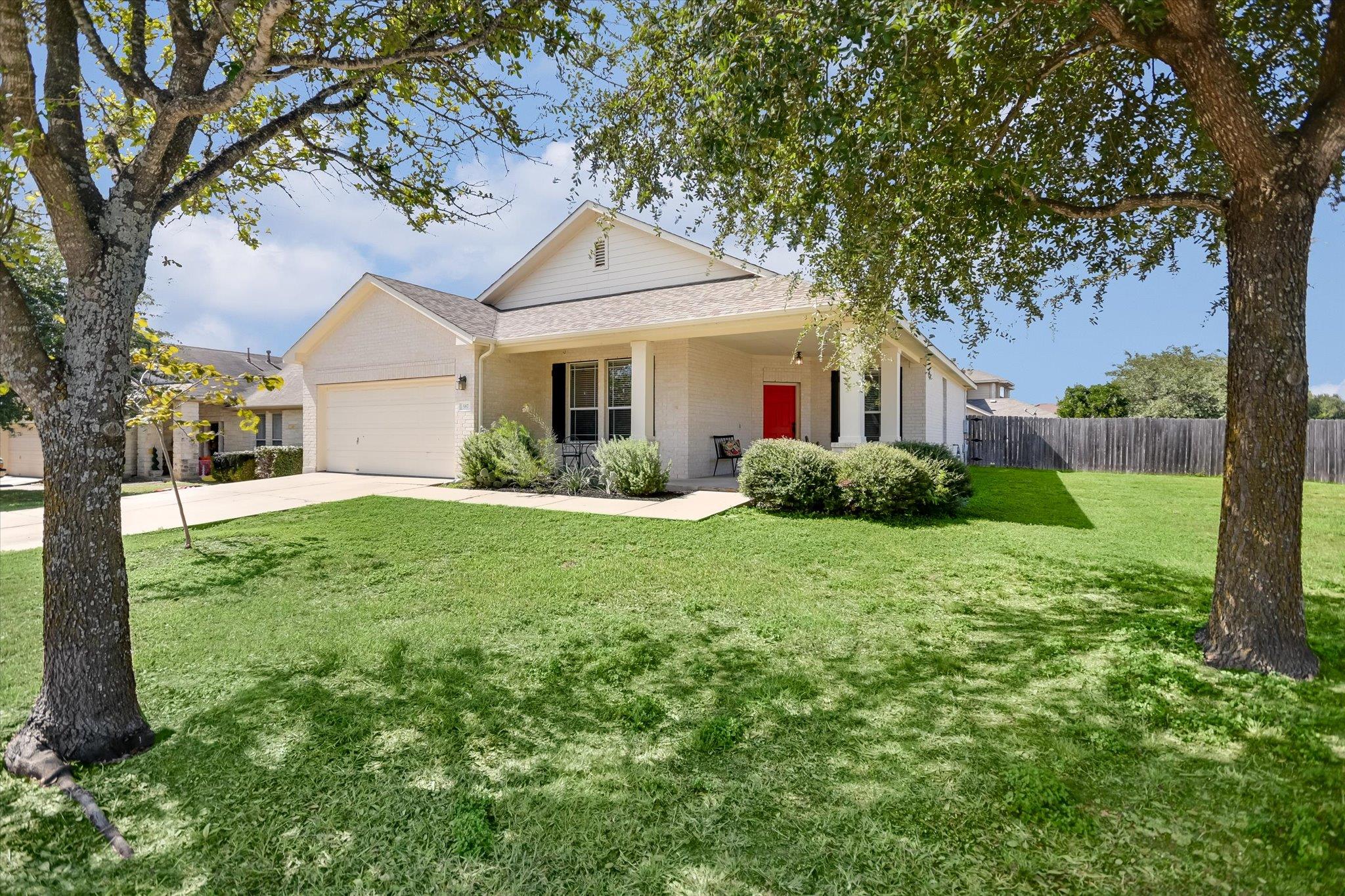 Mature trees shade a manicured front lawn leading