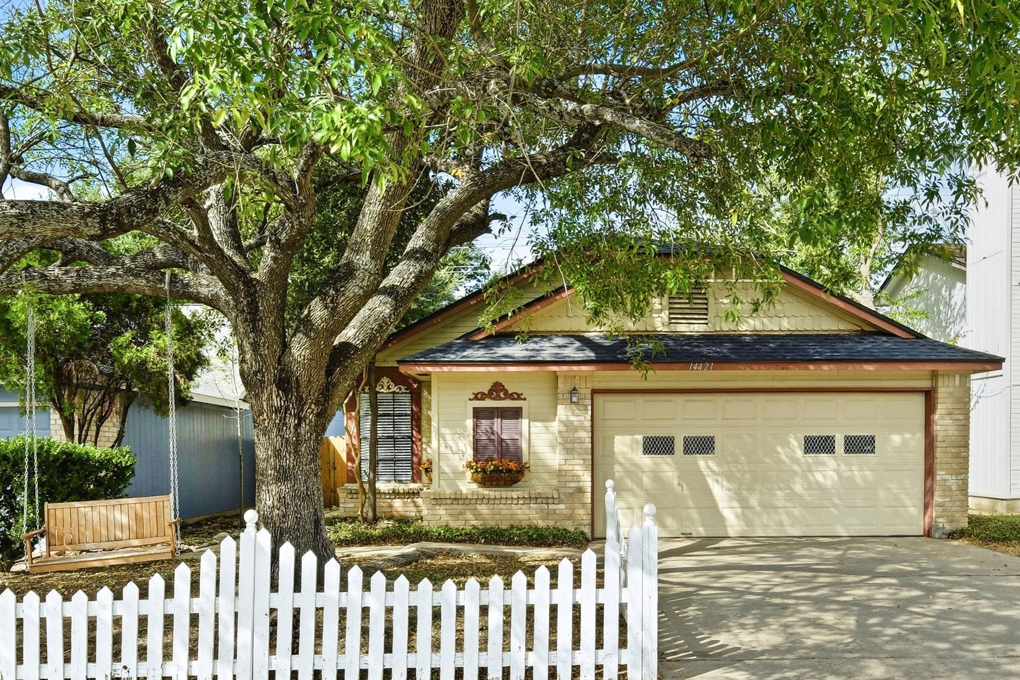 Mature trees shade a charming brick-accented exte