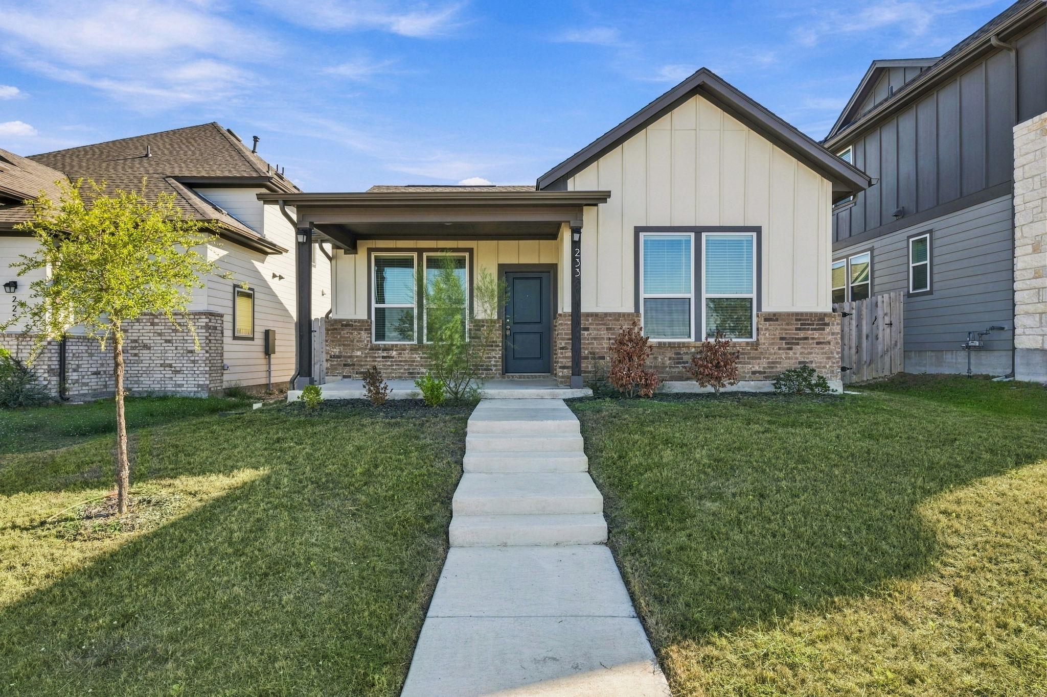 A concrete walkway leads past a grassy lawn to th