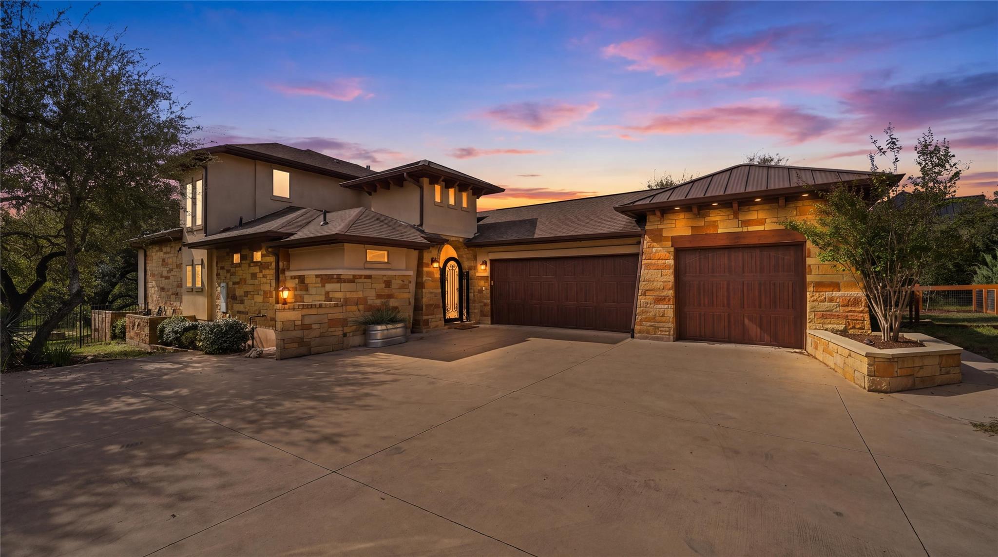 Warm stone elevations meet a spacious concrete dr