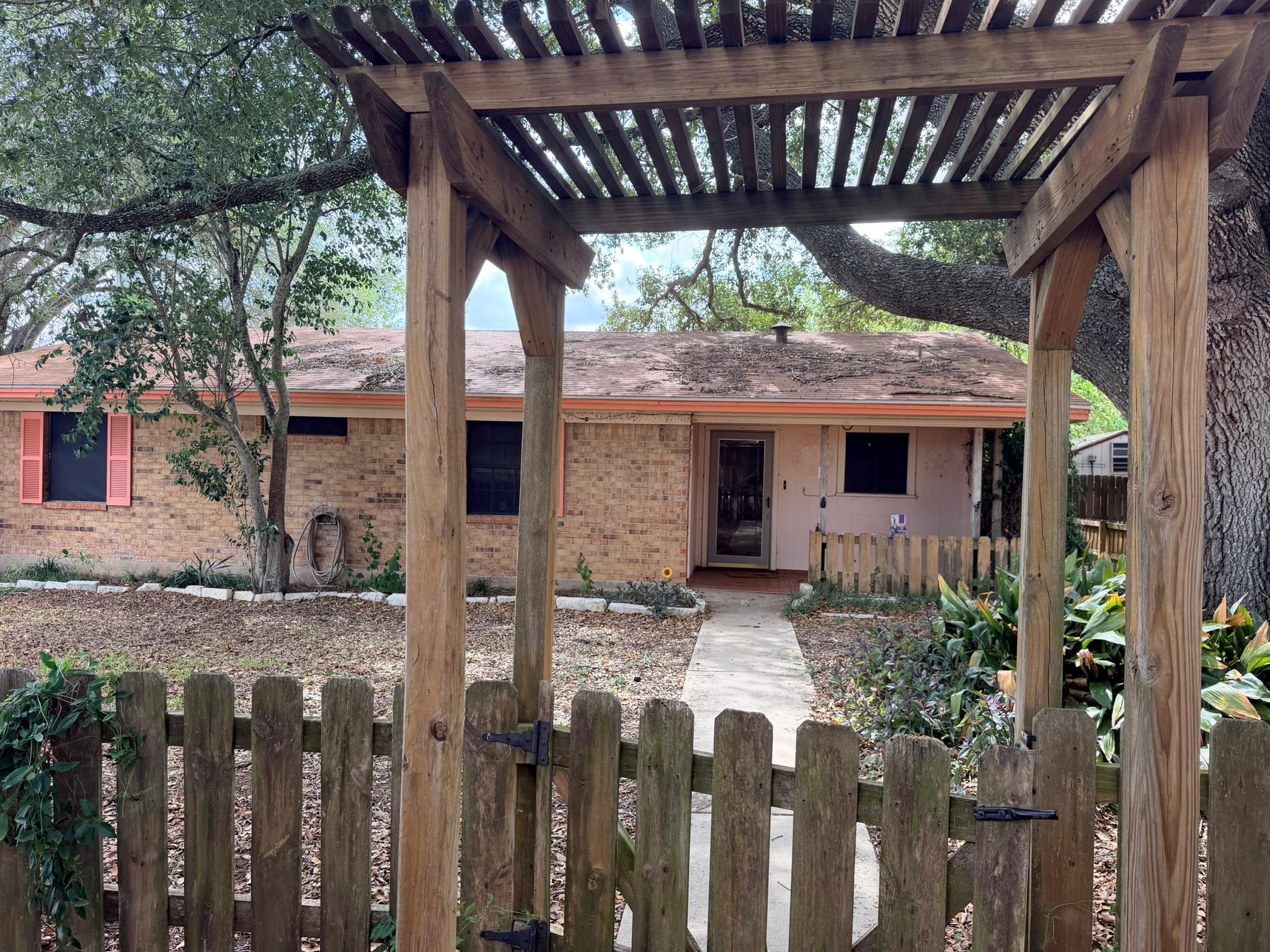 An inviting wooden pergola frames the brick exter