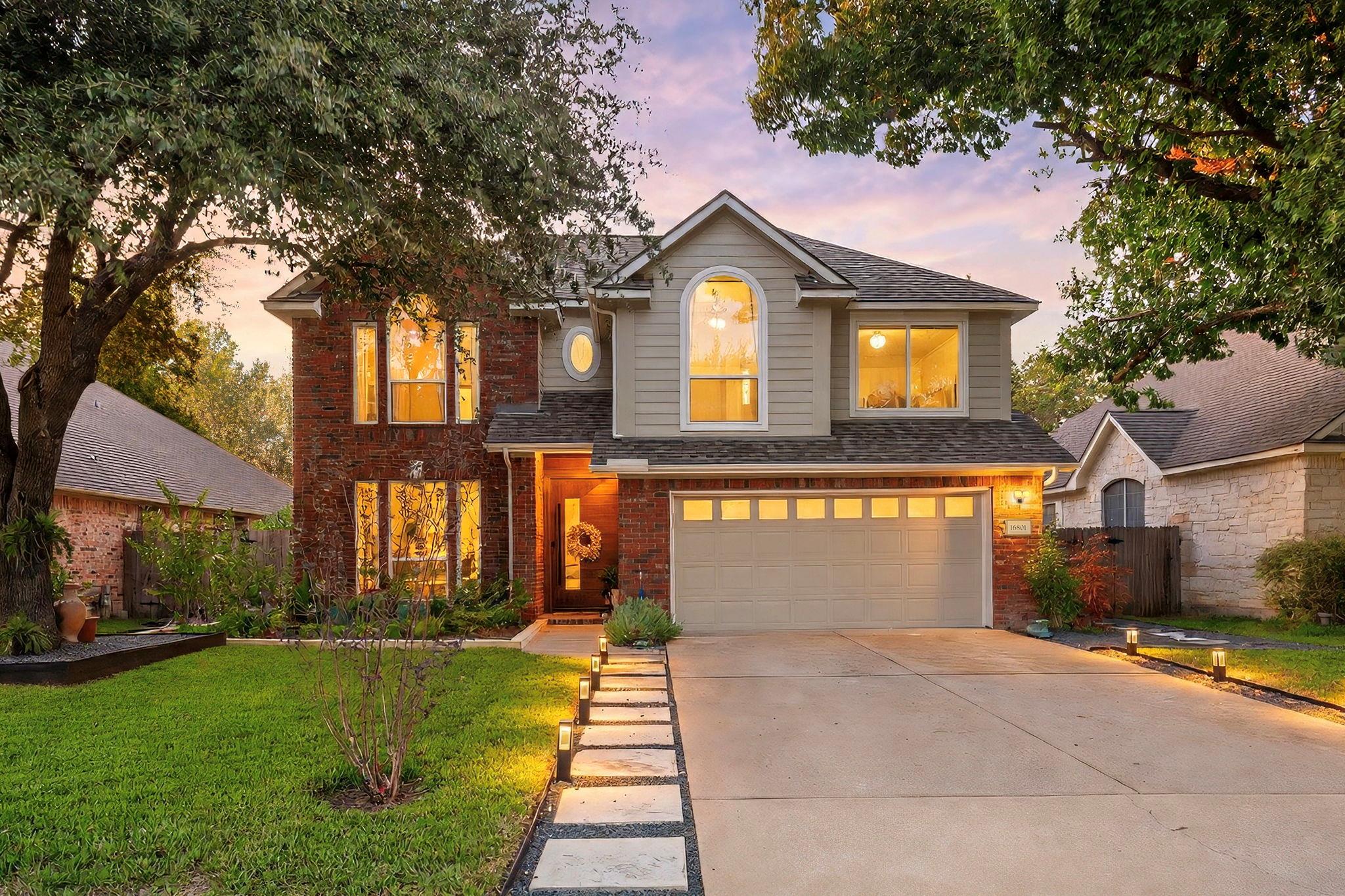 Mature trees frame a classic brick facade accente