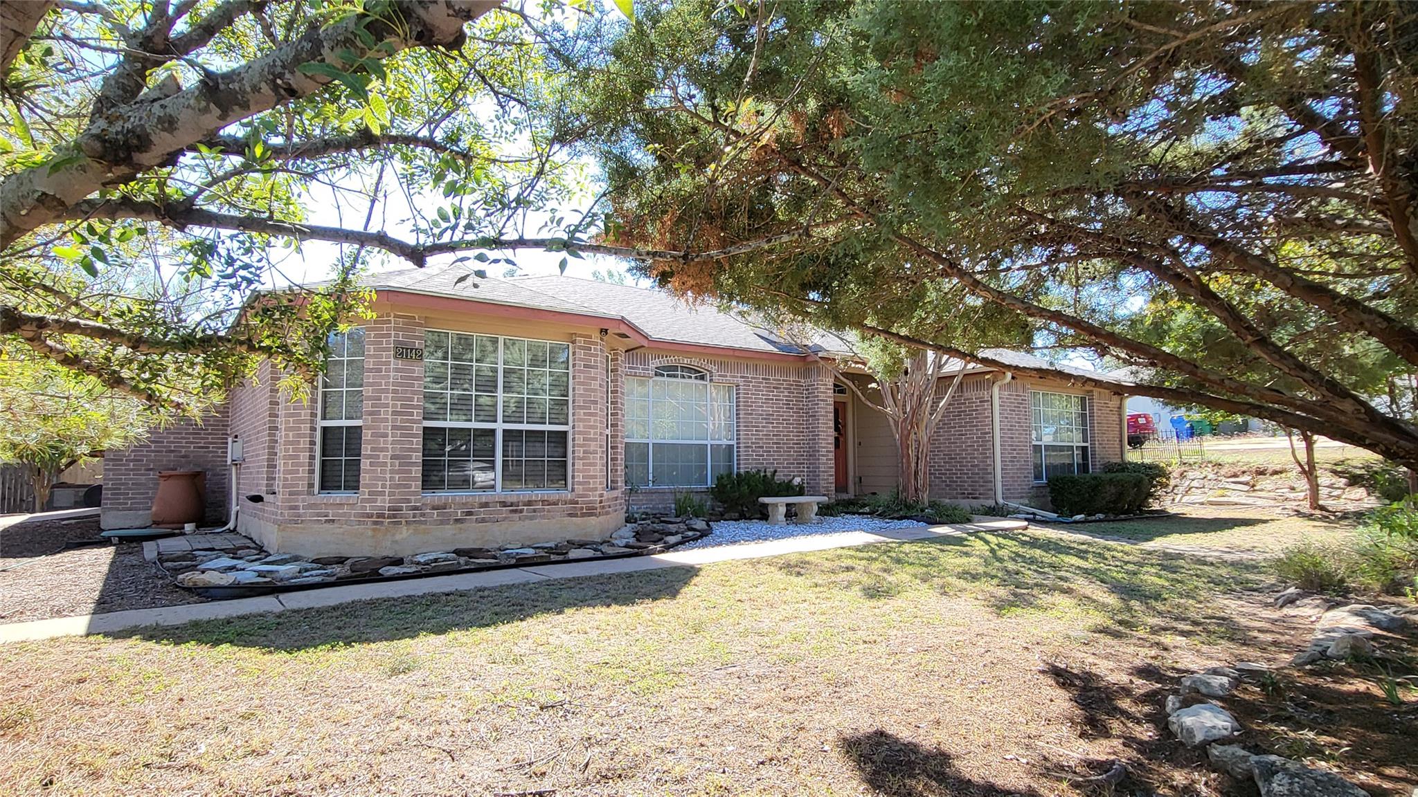 Mature trees frame a classic single-story brick e