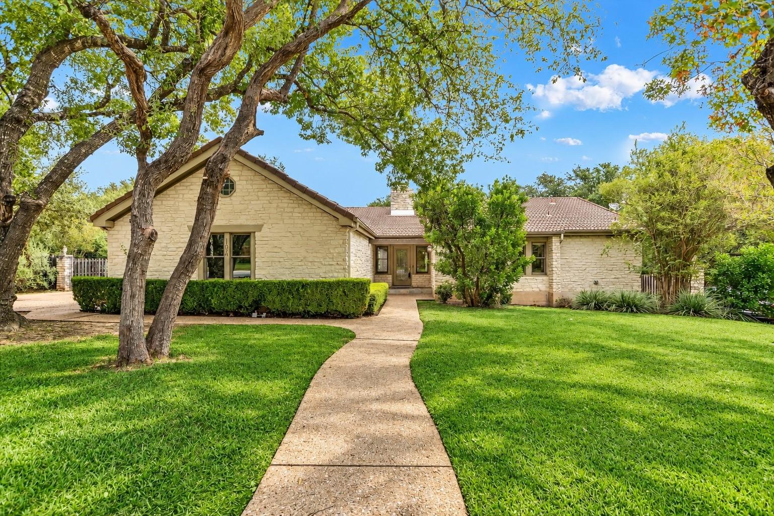 A concrete walkway leads through the verdant lawn