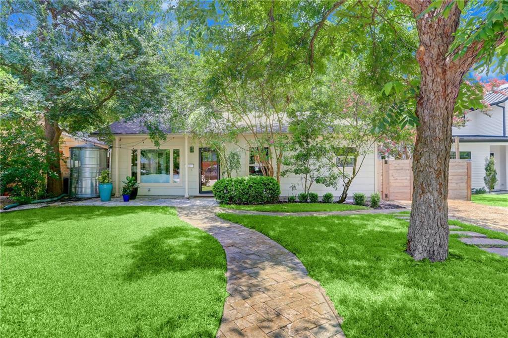 A stone pathway winds through a shaded front lawn