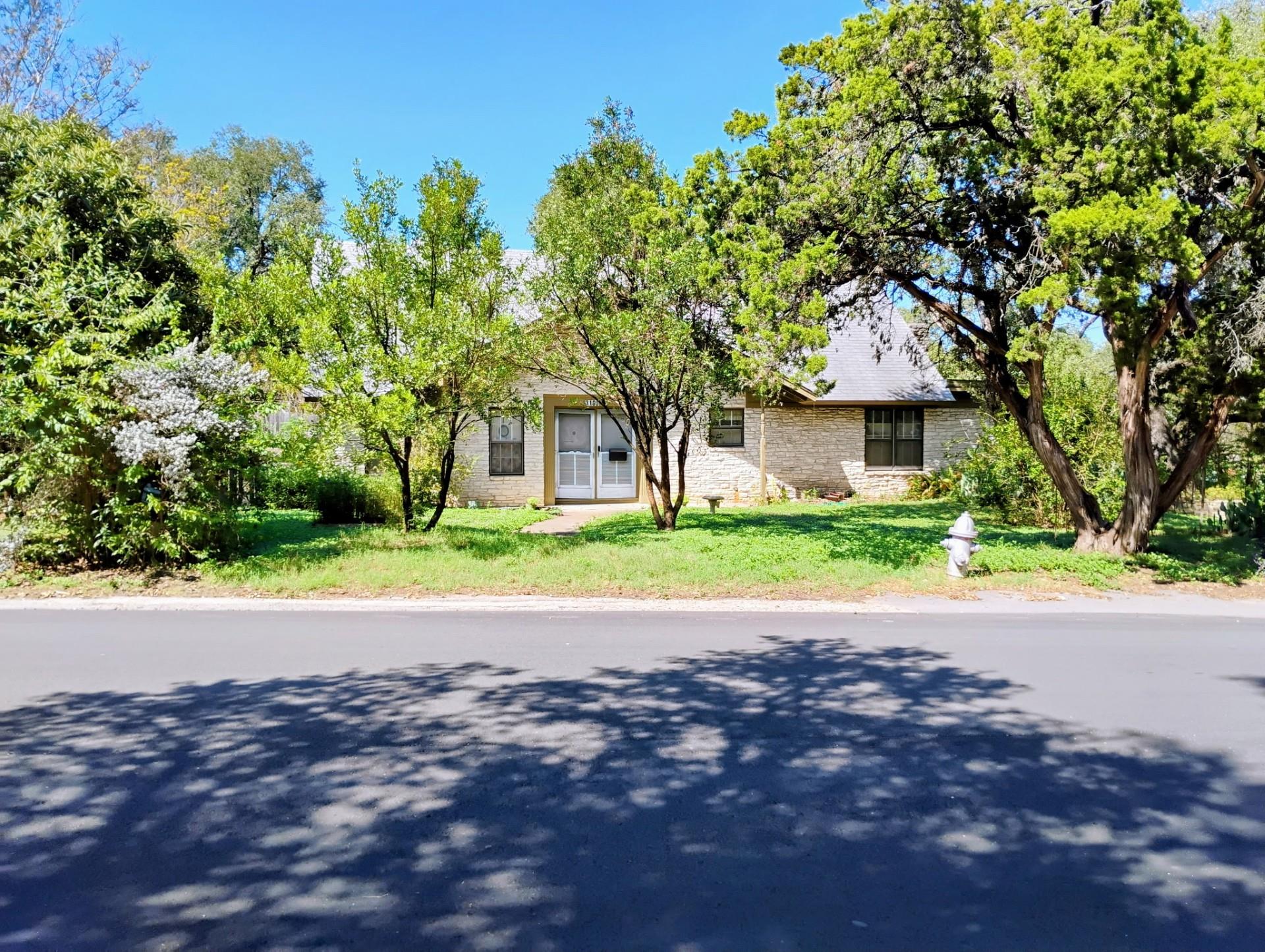Mature trees frame the front of this single-story
