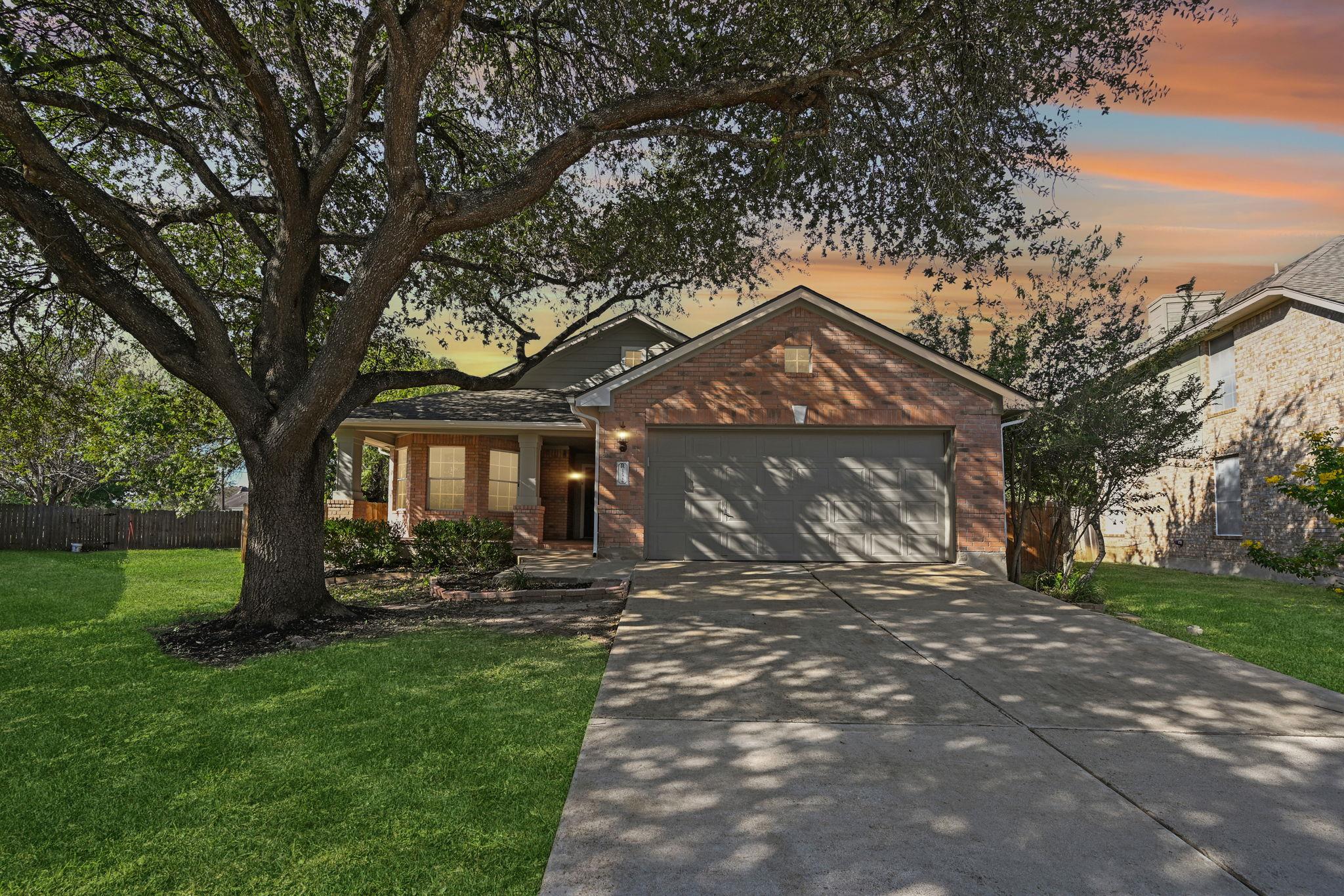 Mature shade trees frame the classic brick exteri