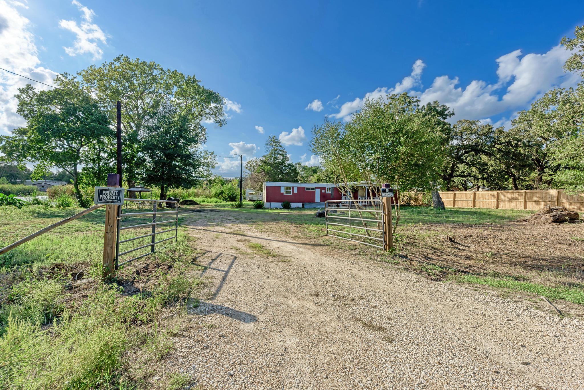An open gated entrance leads along a gravel drive