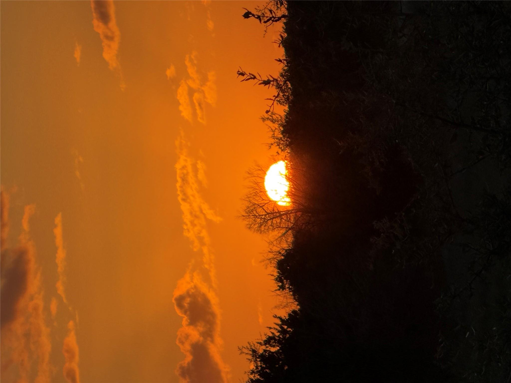 A vibrant orange sunset paints the sky above a ho