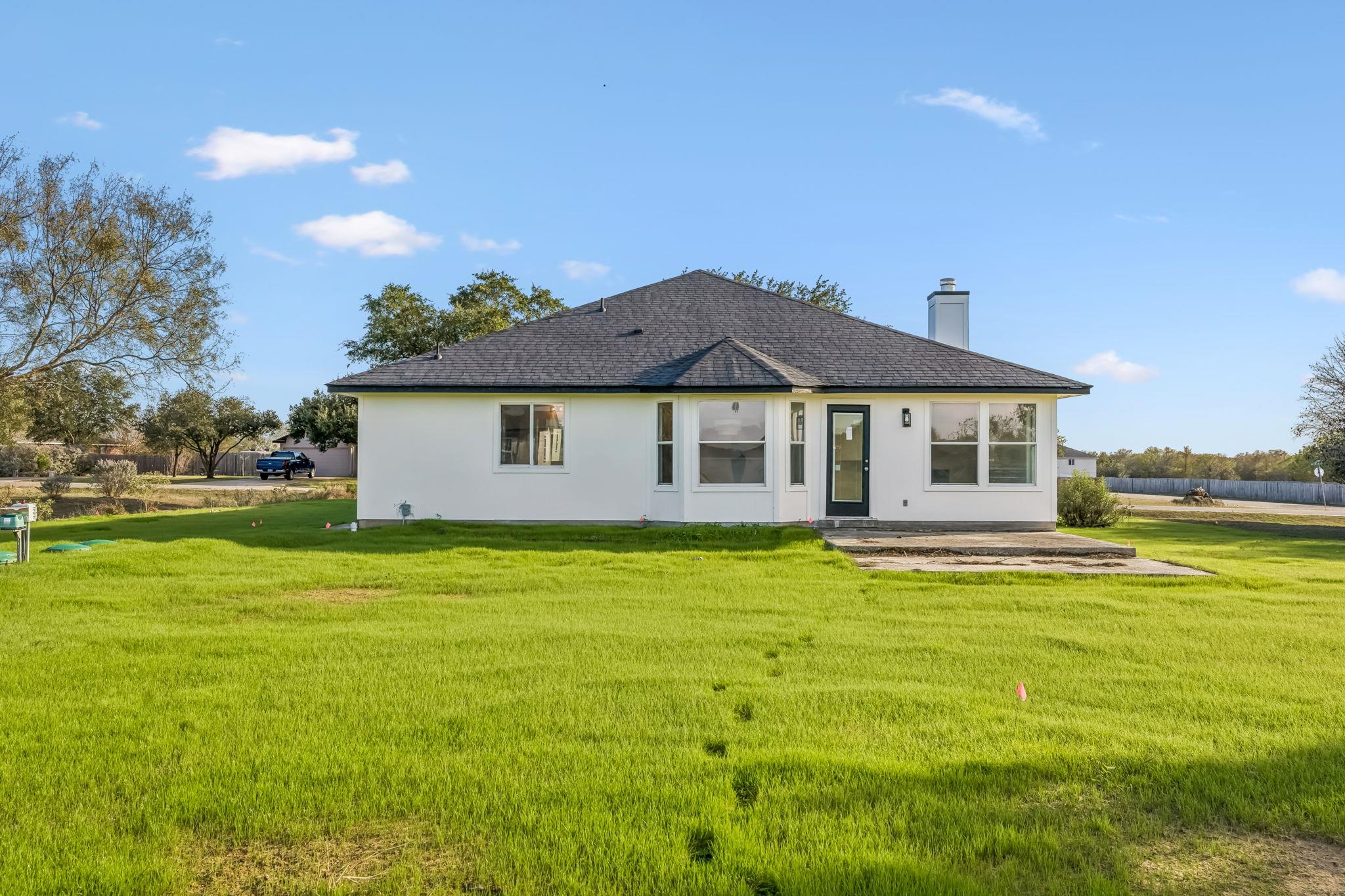 A spacious grassy lawn borders the concrete patio
