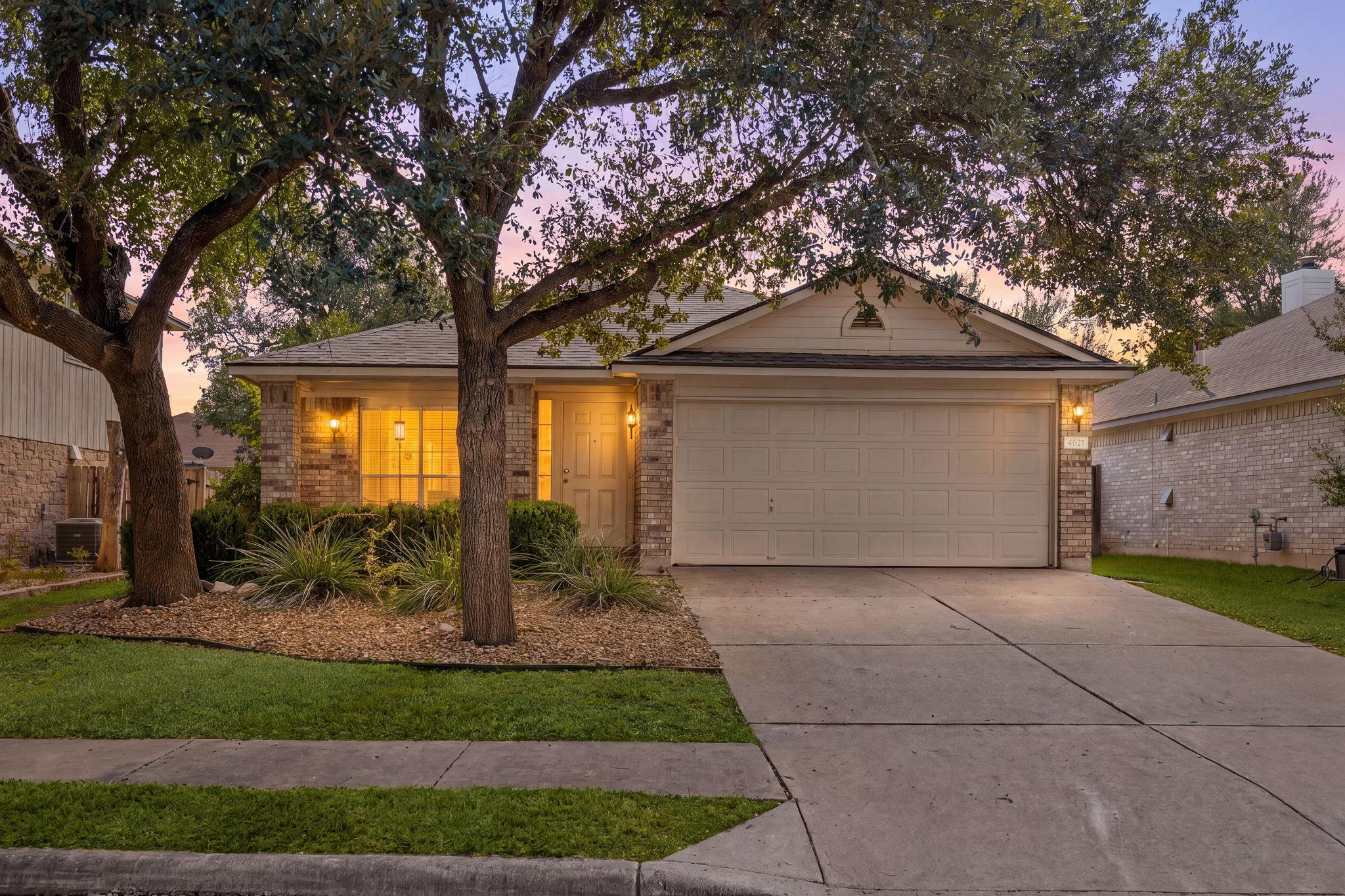 Mature trees shade the neat concrete driveway and