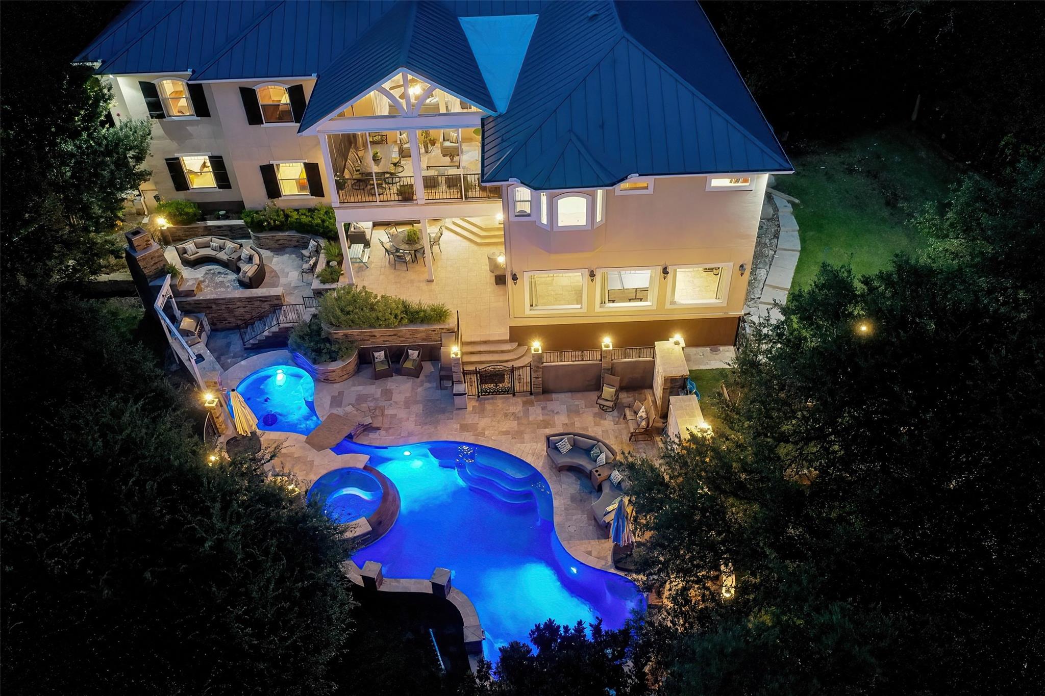 An illuminated pool and multilevel stone patios a