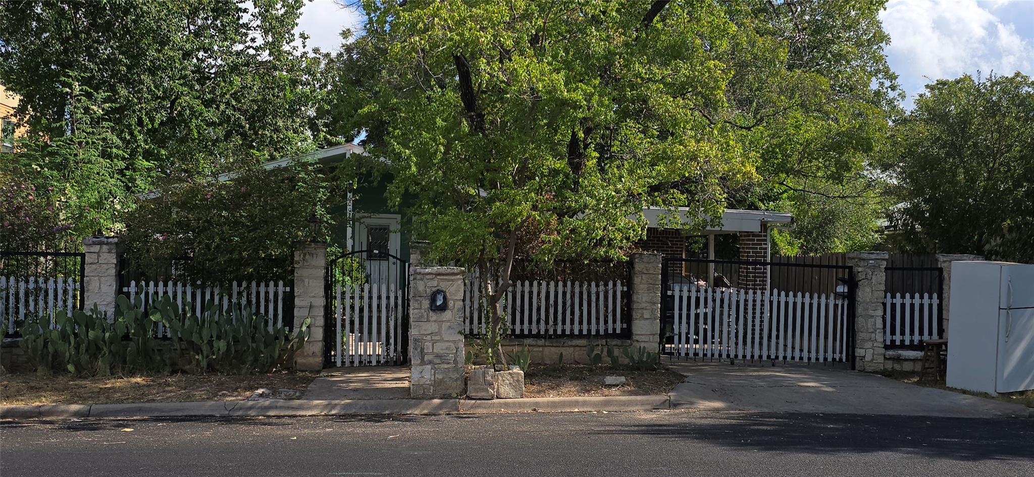 Mature trees frame the stone and picket fence bor