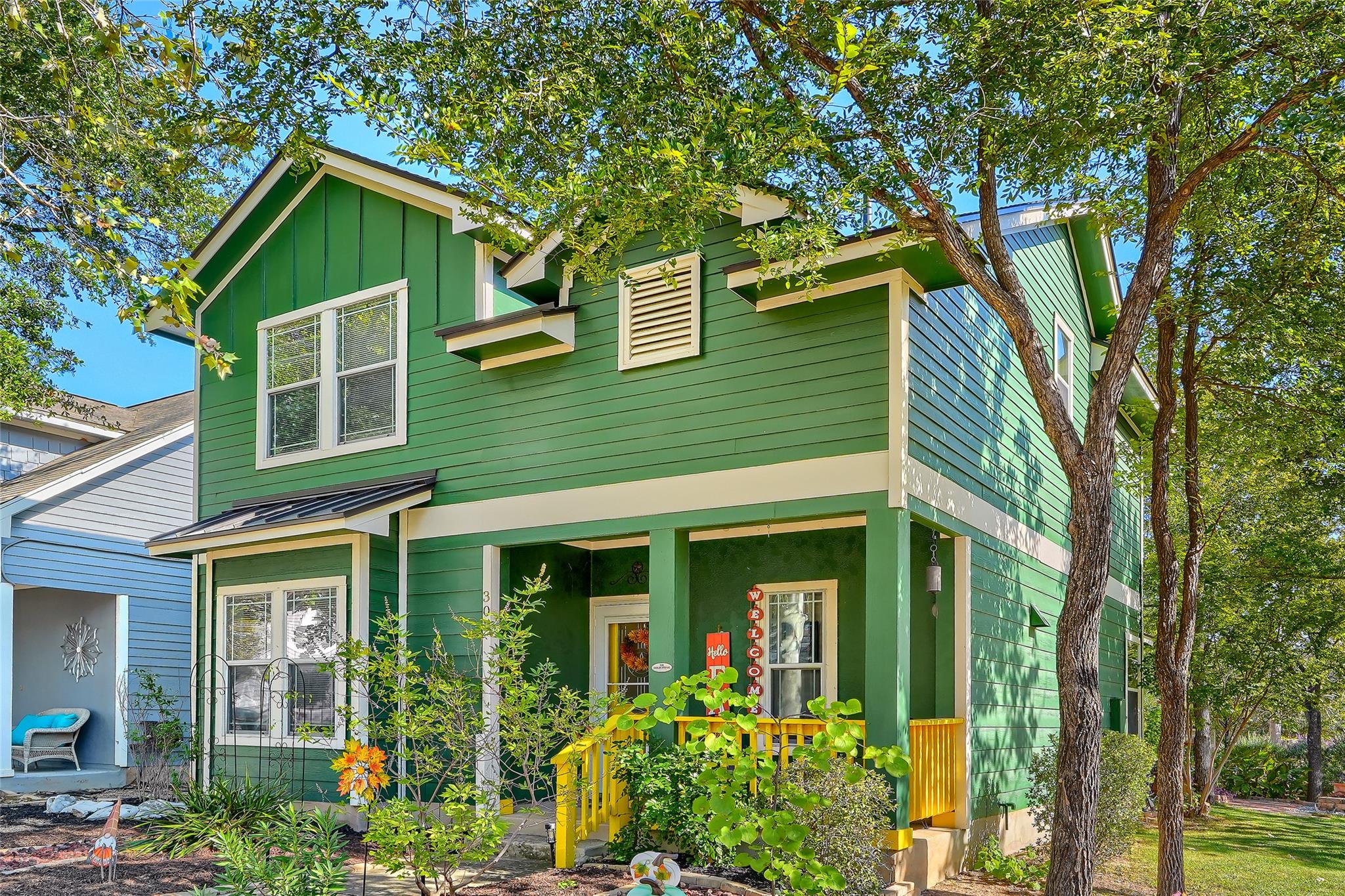 Mature trees frame the charming covered front por