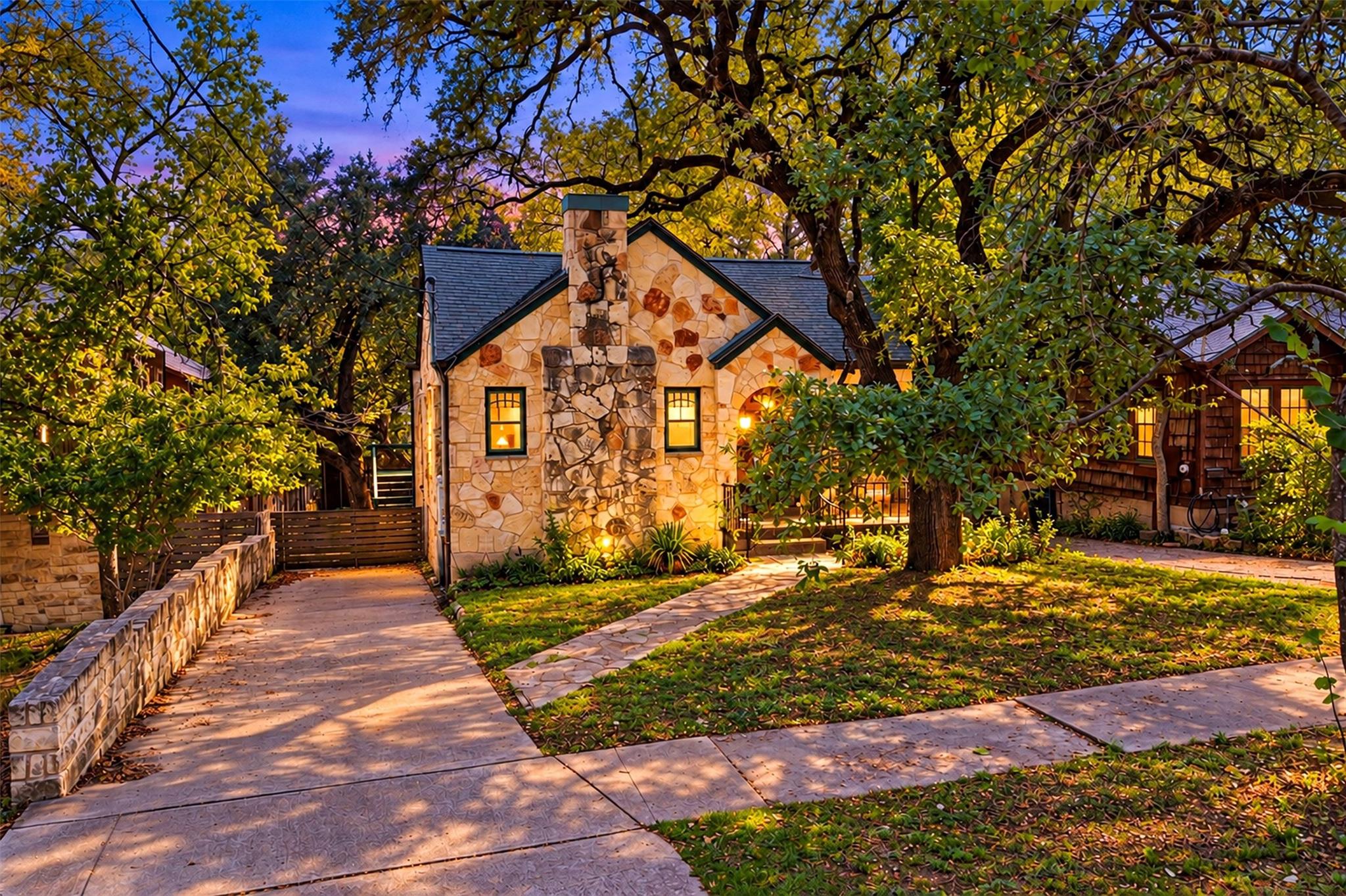 Mature trees shade a charming stone cottage frame