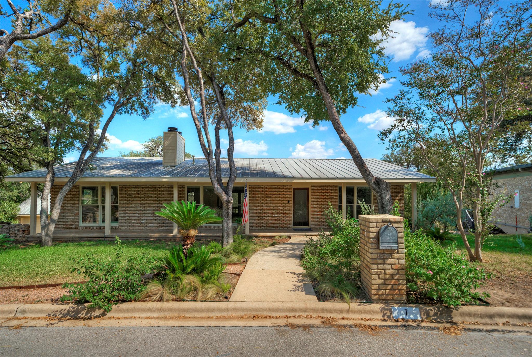 Mature trees shade a classic brick ranch home fea