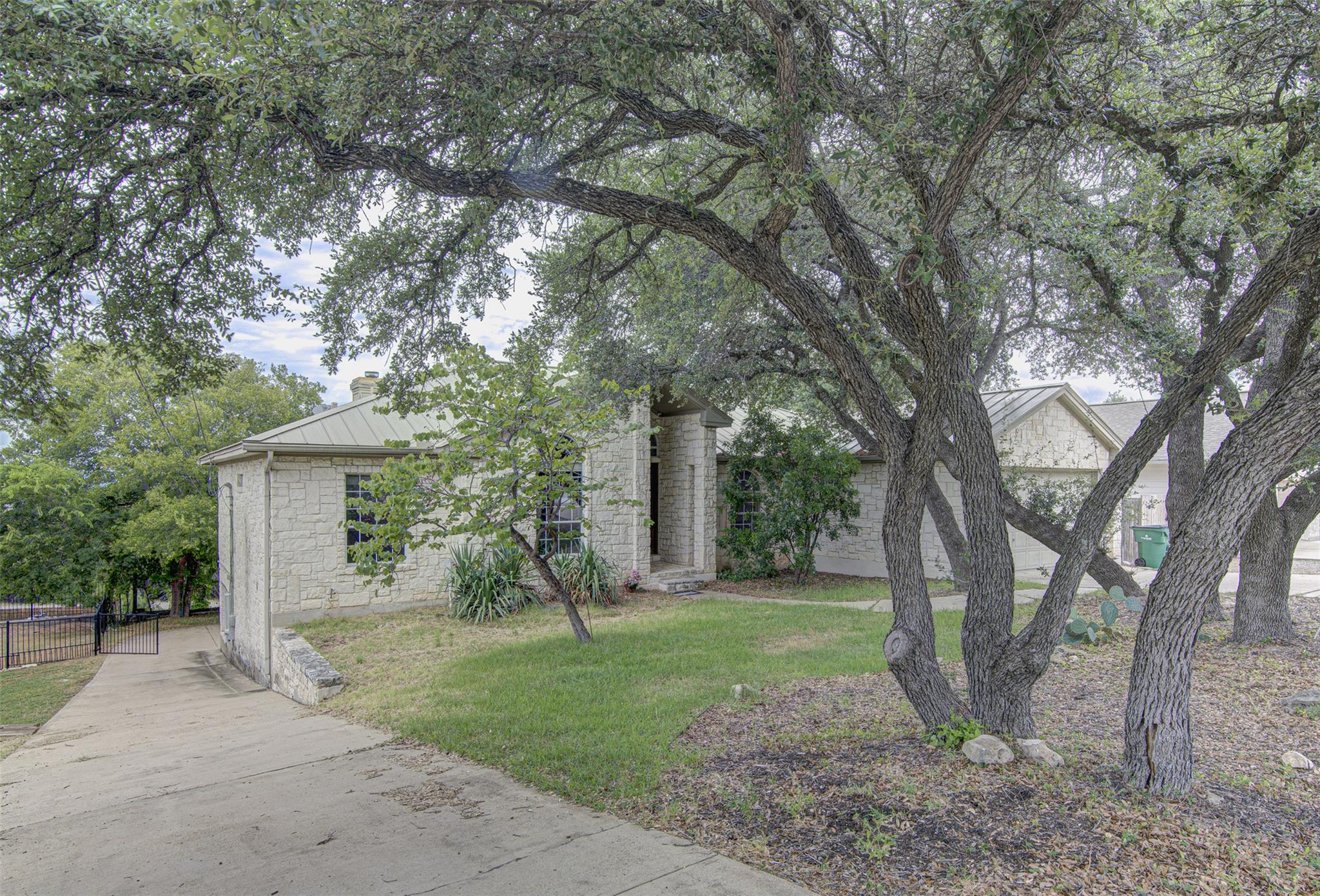 Mature shade trees frame a classic stone facade a