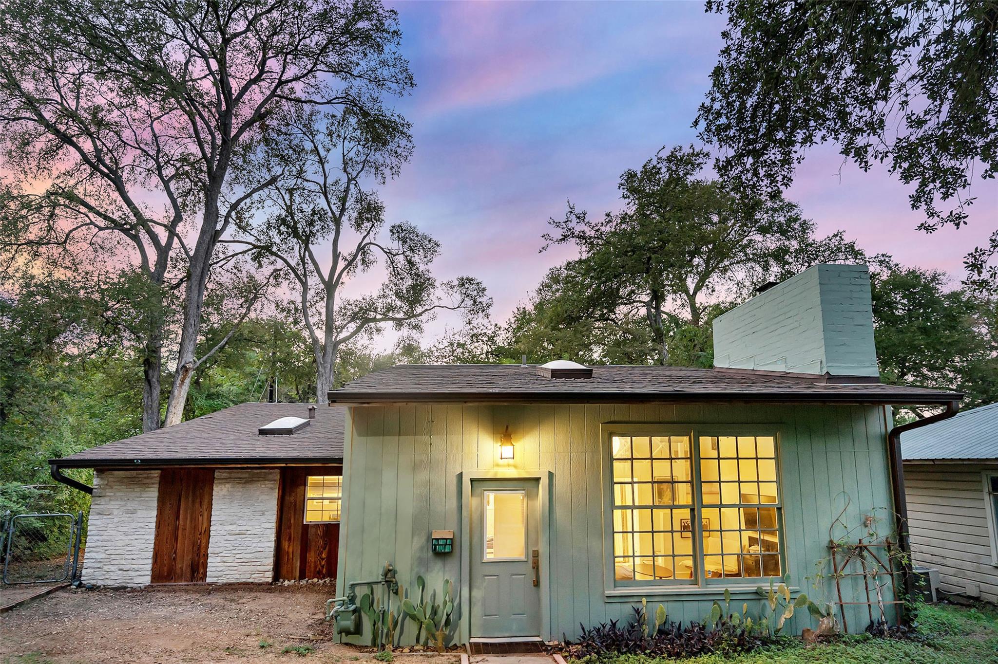 Mature trees frame a charming exterior featuring 