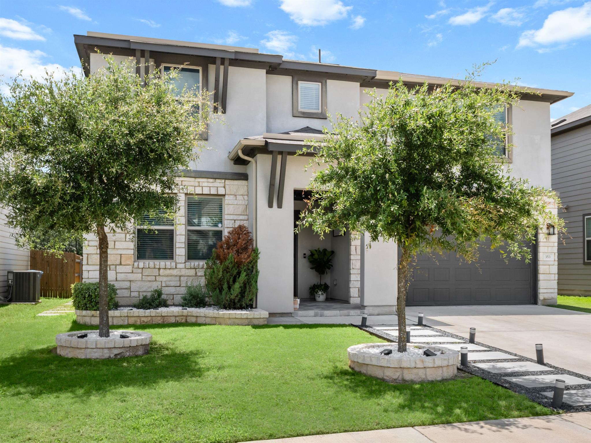 A stone and stucco exterior pairs with manicured 