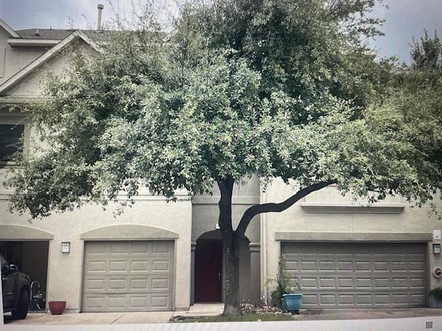 Mature shade trees frame the exterior entry of th