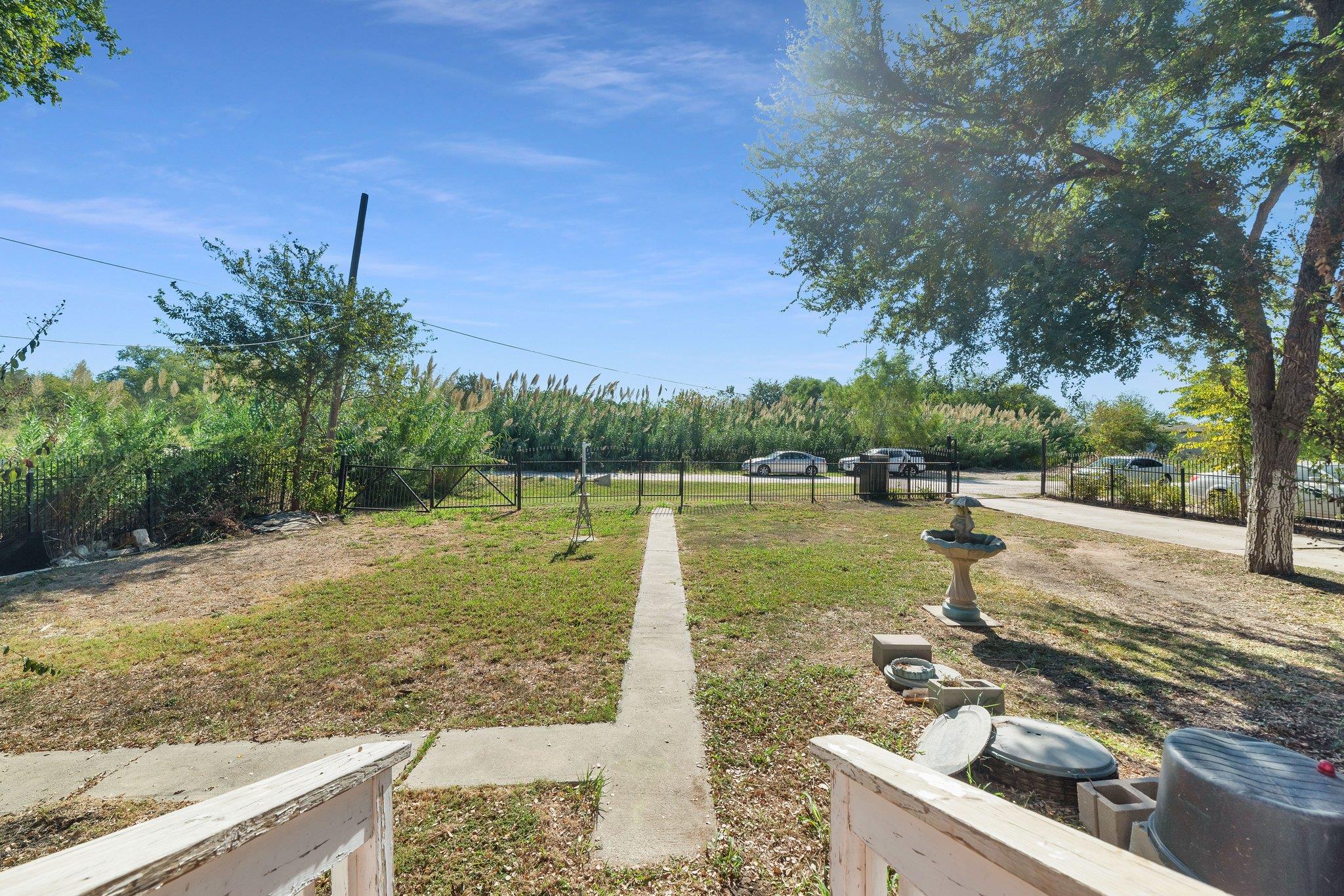 A concrete walkway leads through a fenced grassy 