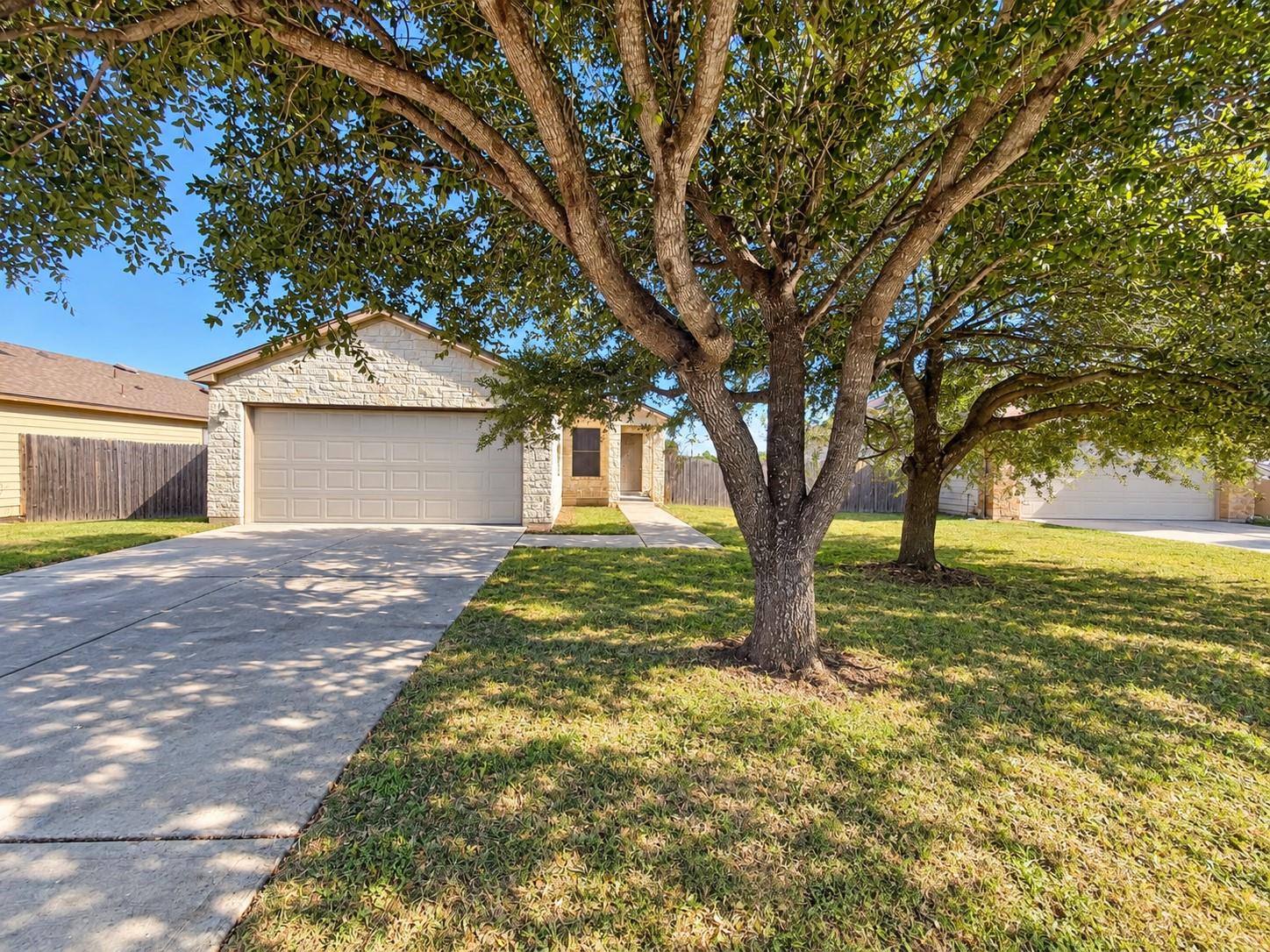 Mature shade trees frame a concrete driveway lead