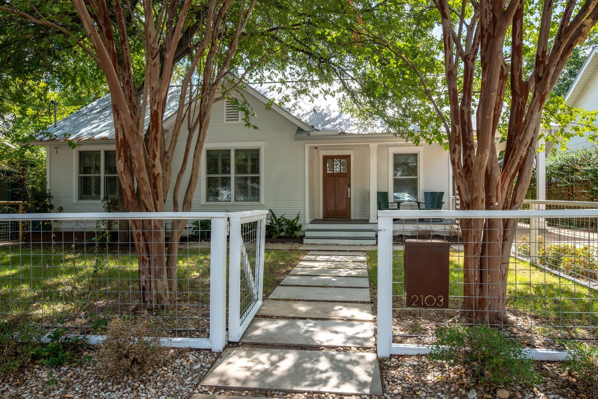 Mature trees shade a welcoming front porch and pa