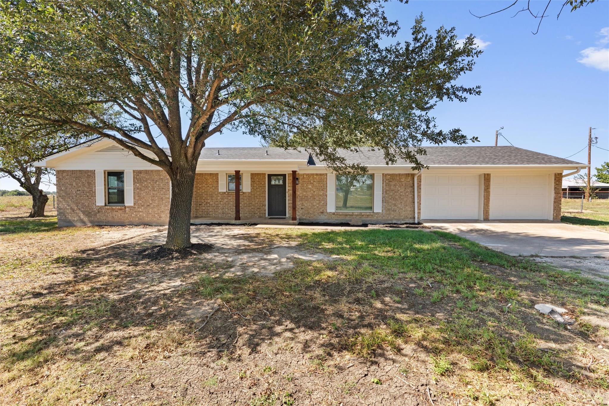 Mature trees shade a classic brick ranch facade f