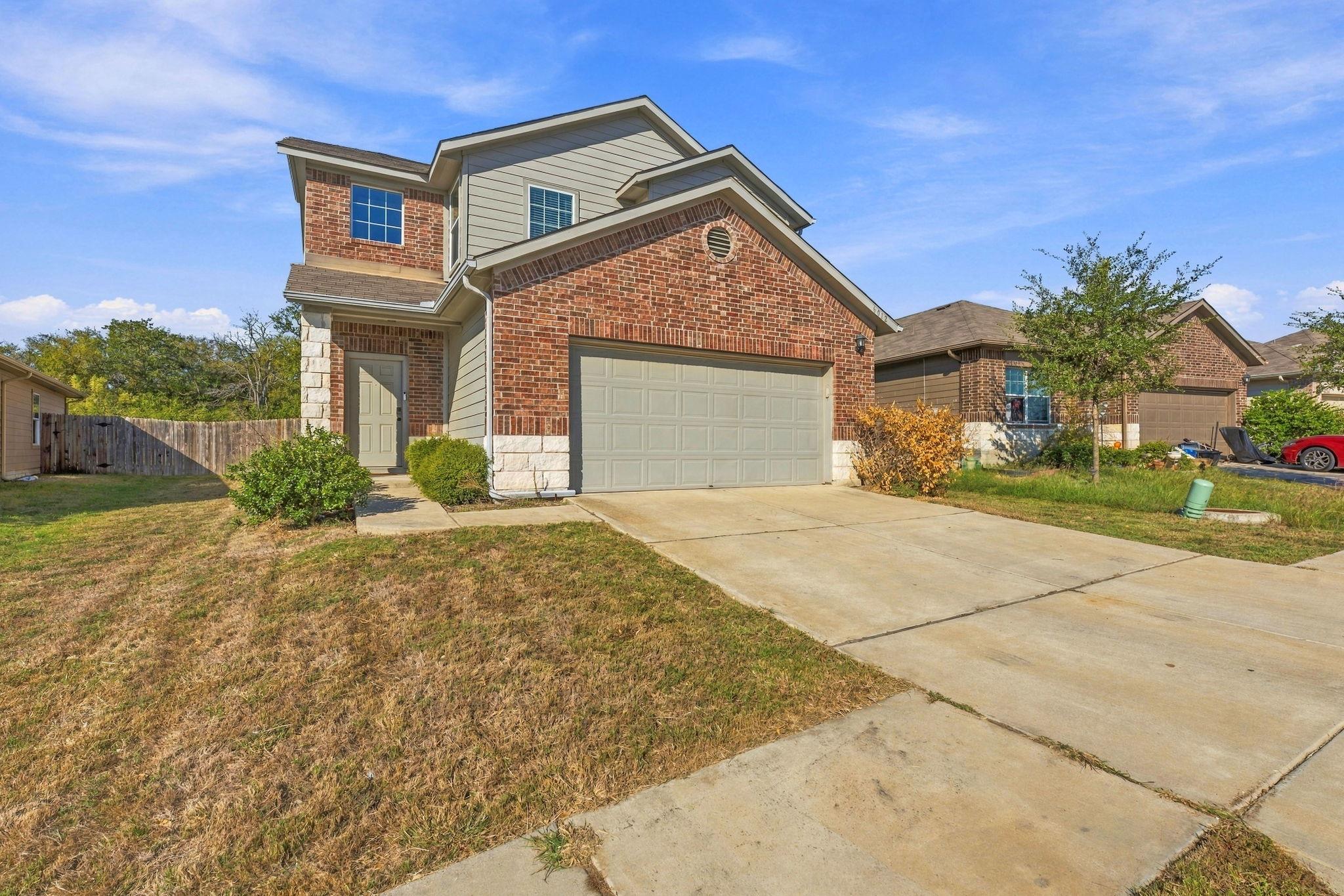 An inviting two-story brick exterior features a s