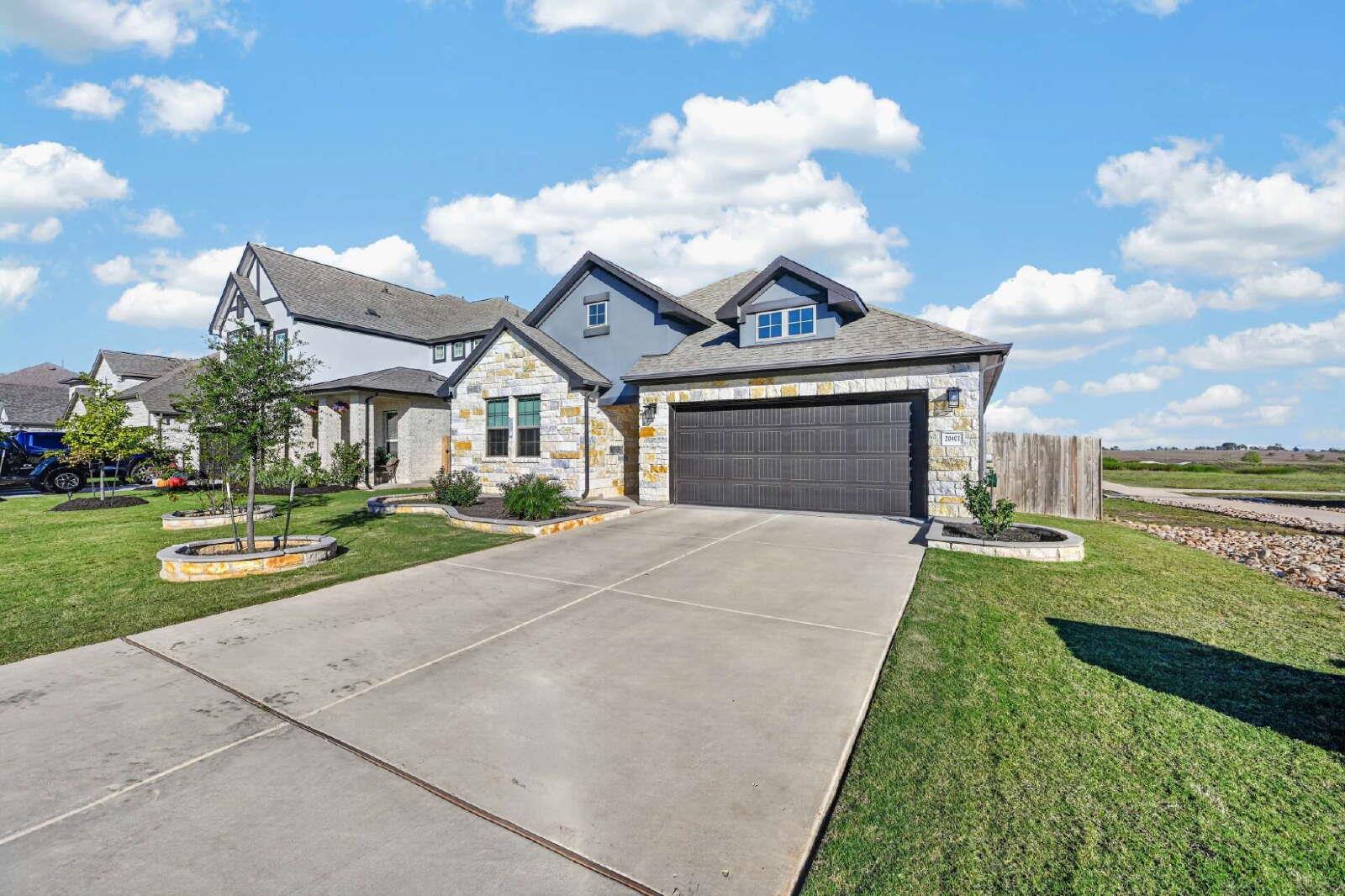 A wide concrete driveway leads toward the stone a