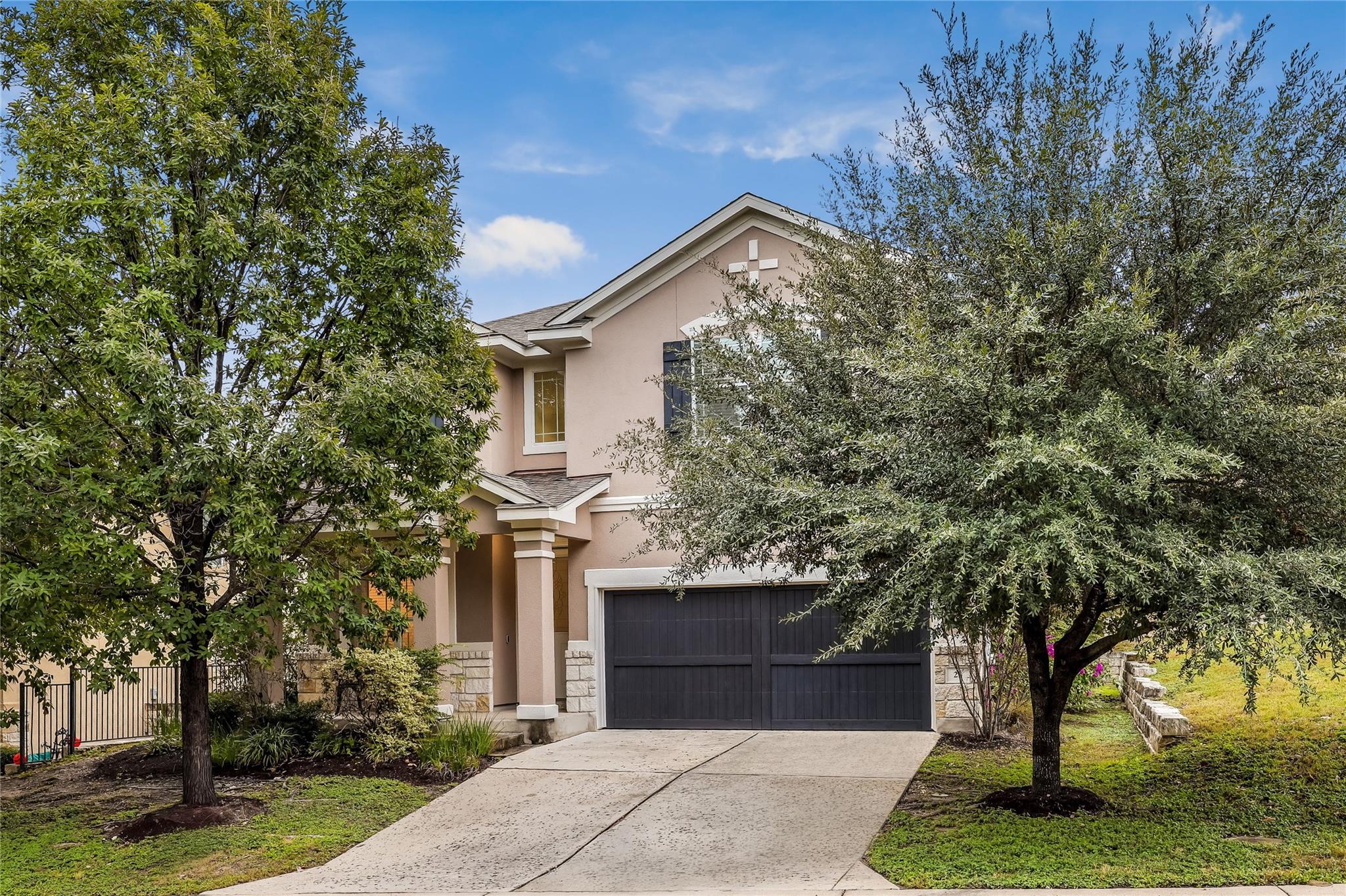 Mature trees frame the stone-accented facade and 